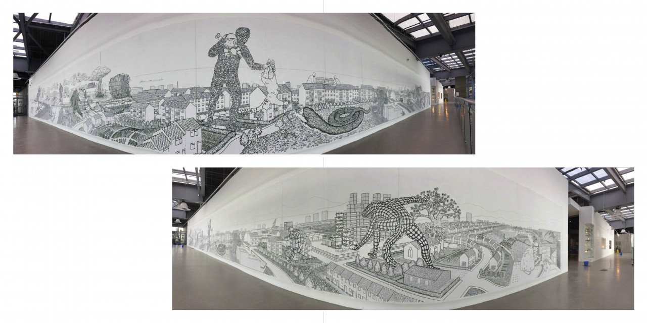  Image description: An open page spread of a book showing two install photographs of a very long white wall in a gallery, on which a black line drawing depicts a scene of hundred foot tall creatures – one human-like and one lizard-like – rampaging th