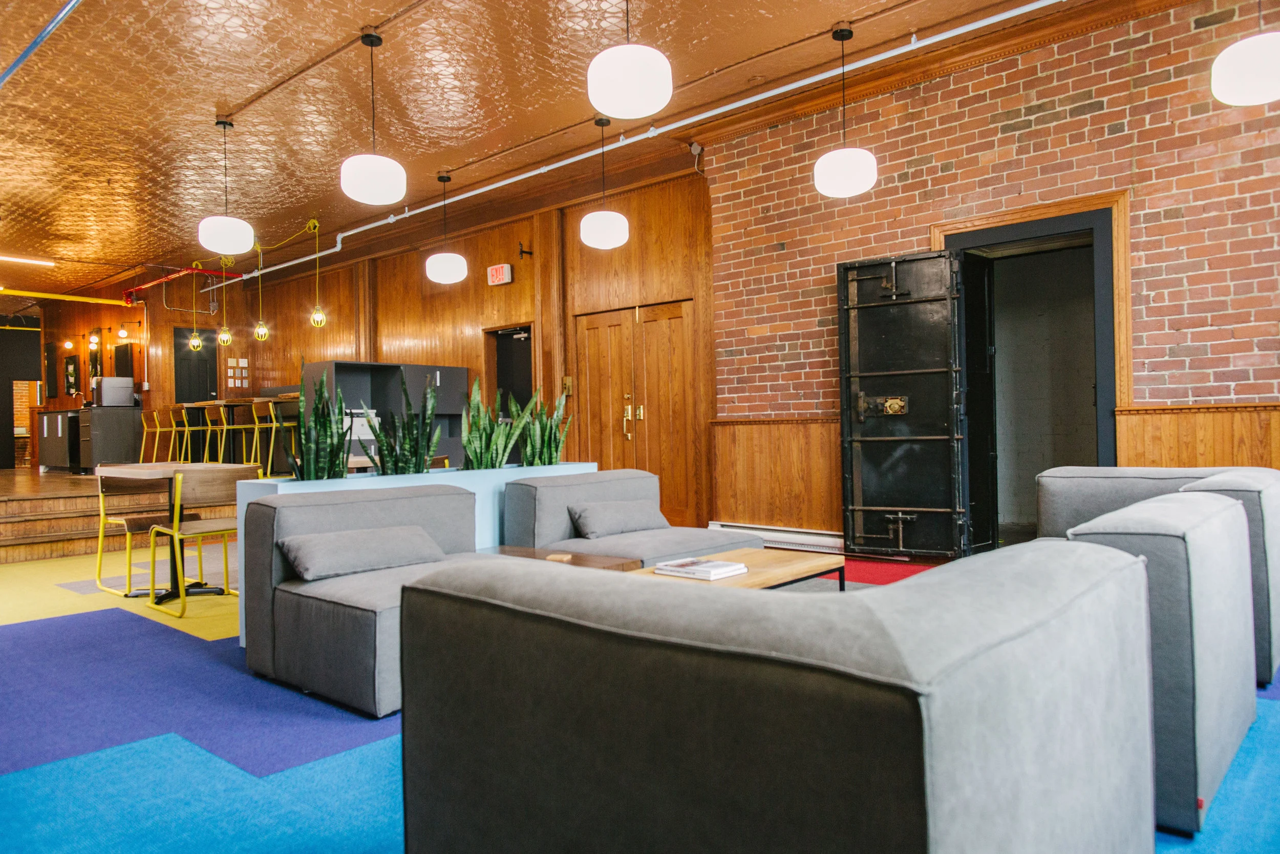 The Concourse lounge at USTATION Harbourfront in Saint John: brick, wood panelling and the old bank vault door