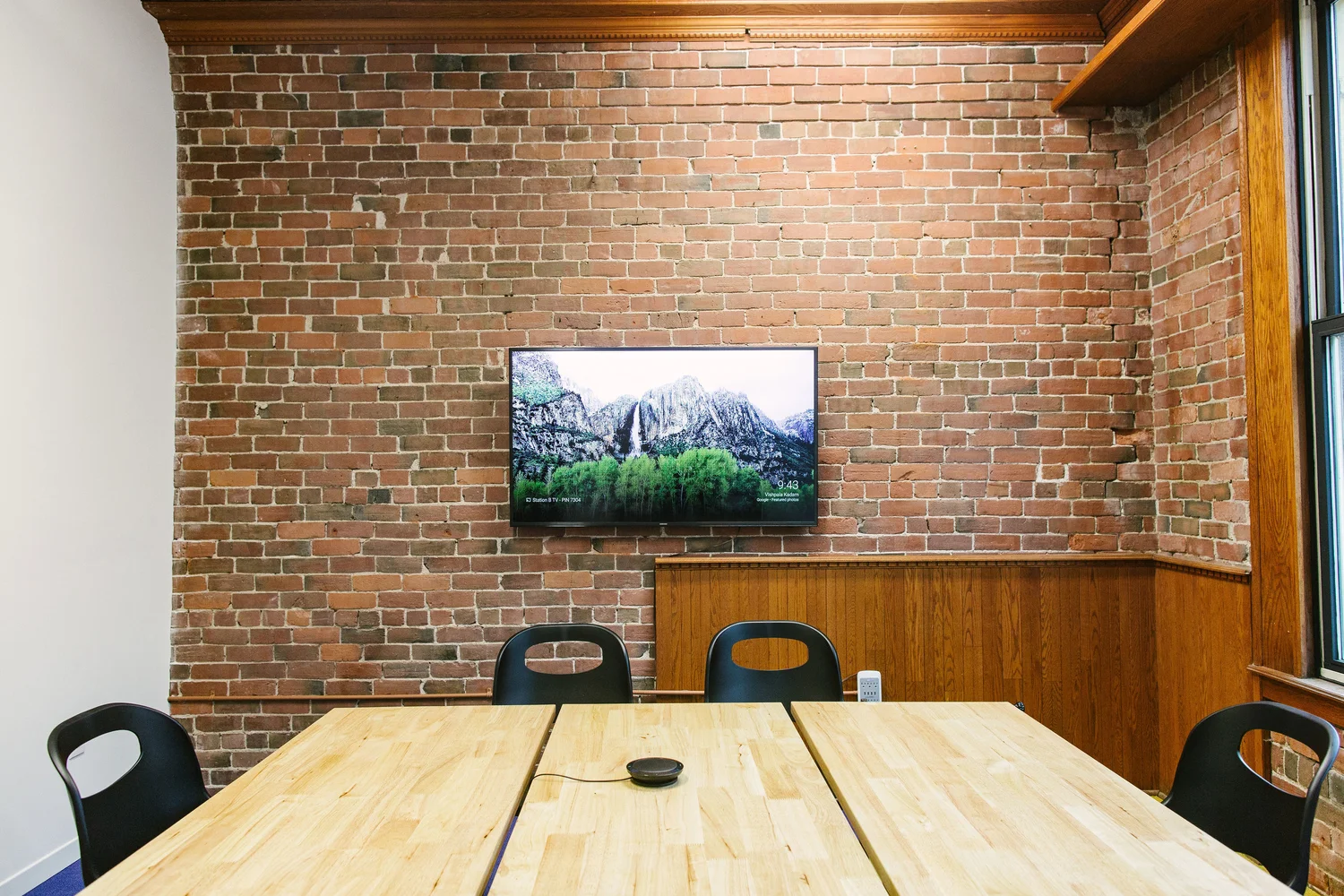The MoonShot room: brick wall, wall-mounted TV and meeting table