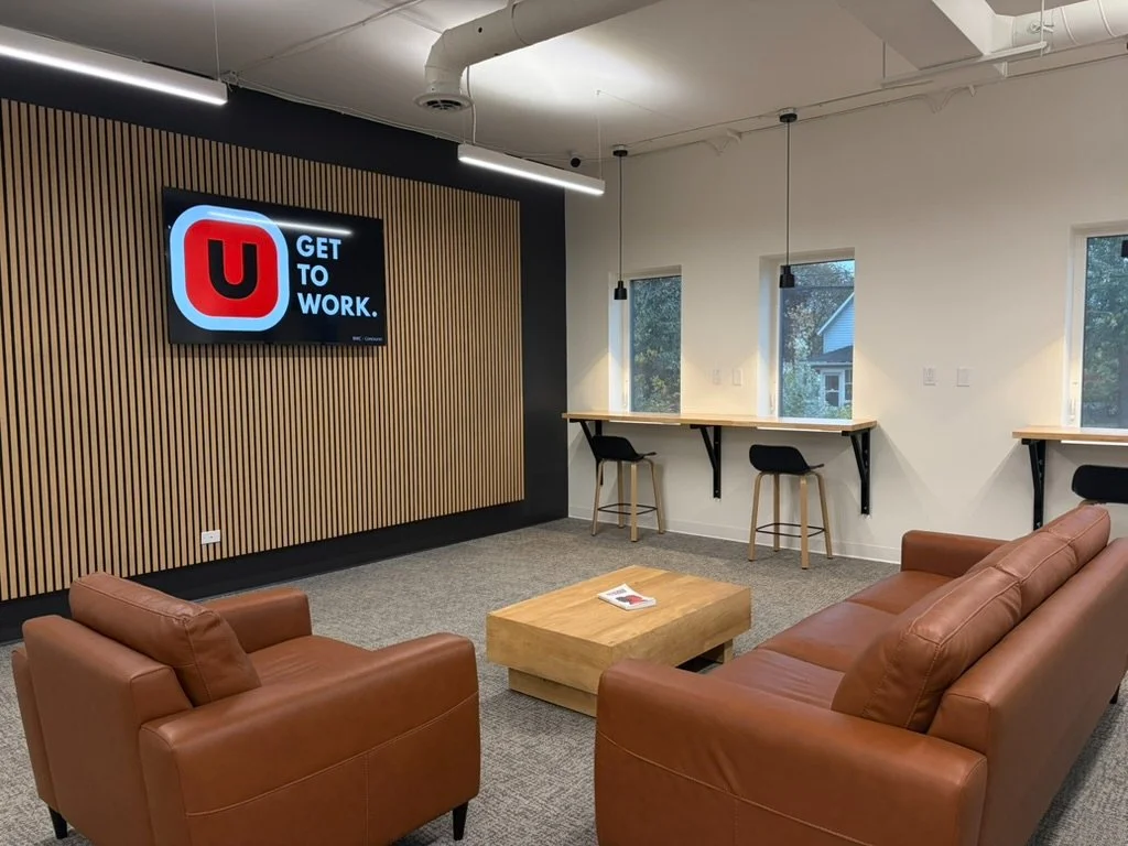 The Concourse at USTATION Miramichi: leather chairs, a coffee table and the USTATION screen