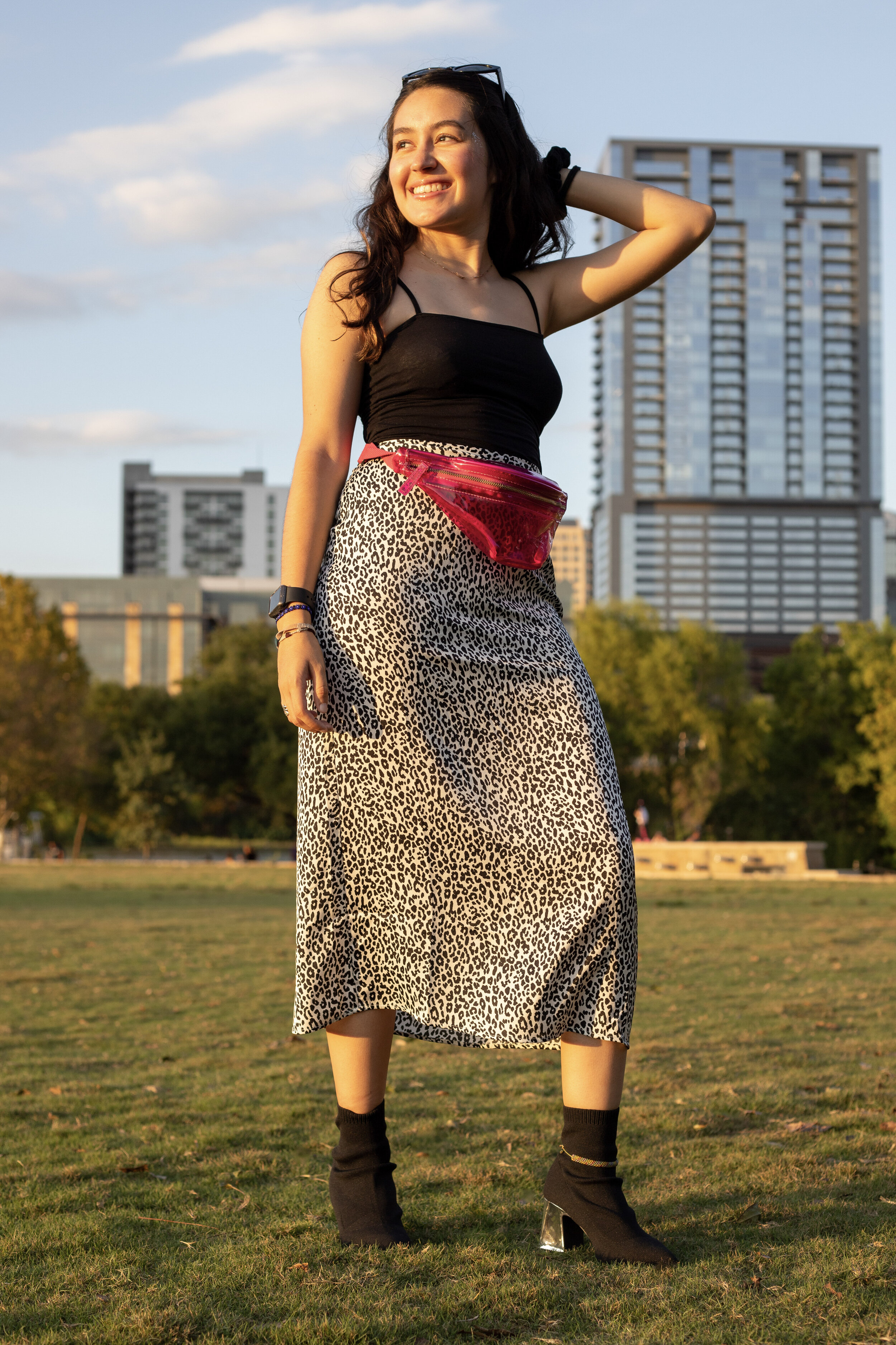  Outfit three has a spaghetti strap black top, a long cheetah skirt, black sock boots, and a pop of color with a pink fanny pack. 