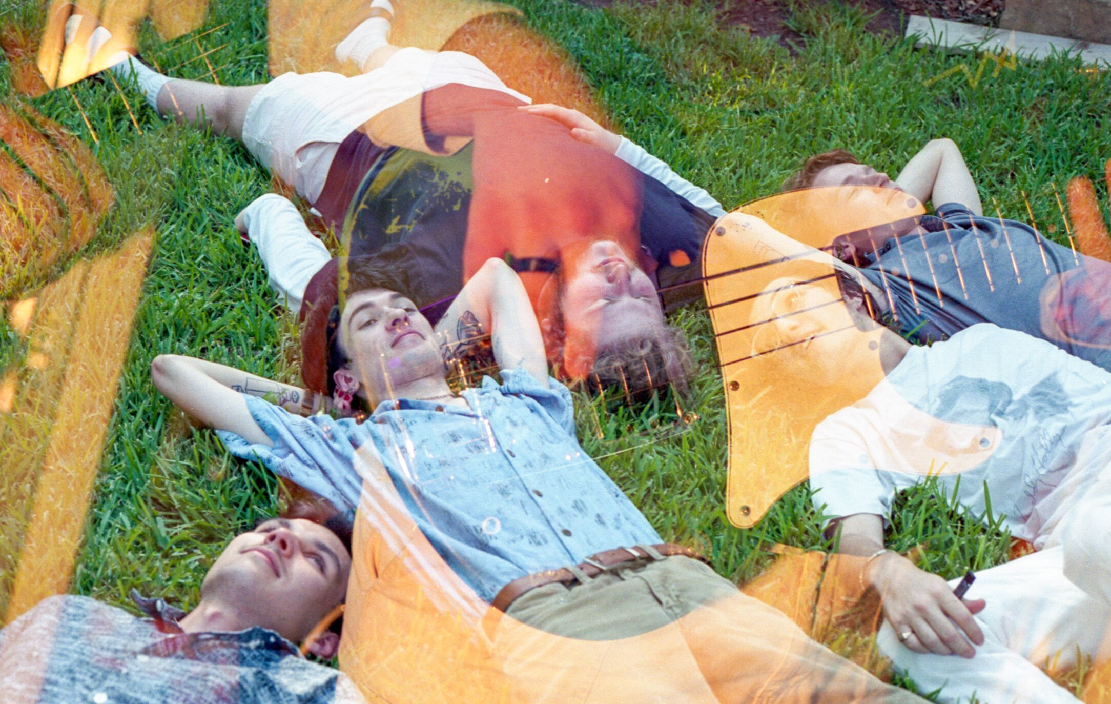  The band laying in their backyard double exposed with Declan playing bass. 
