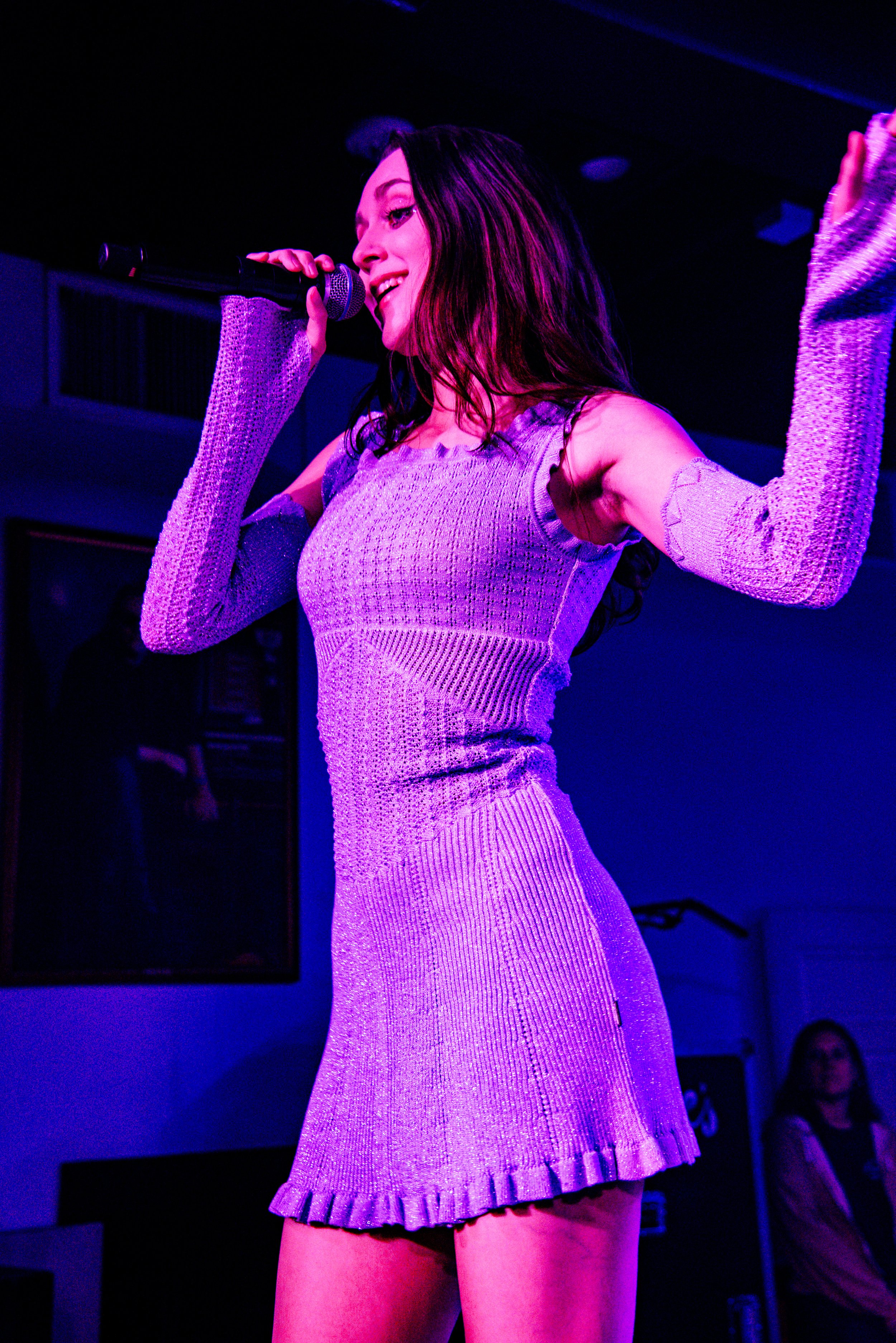  Em Beihold performs as her purple knit dress sparkles in the stage light. 