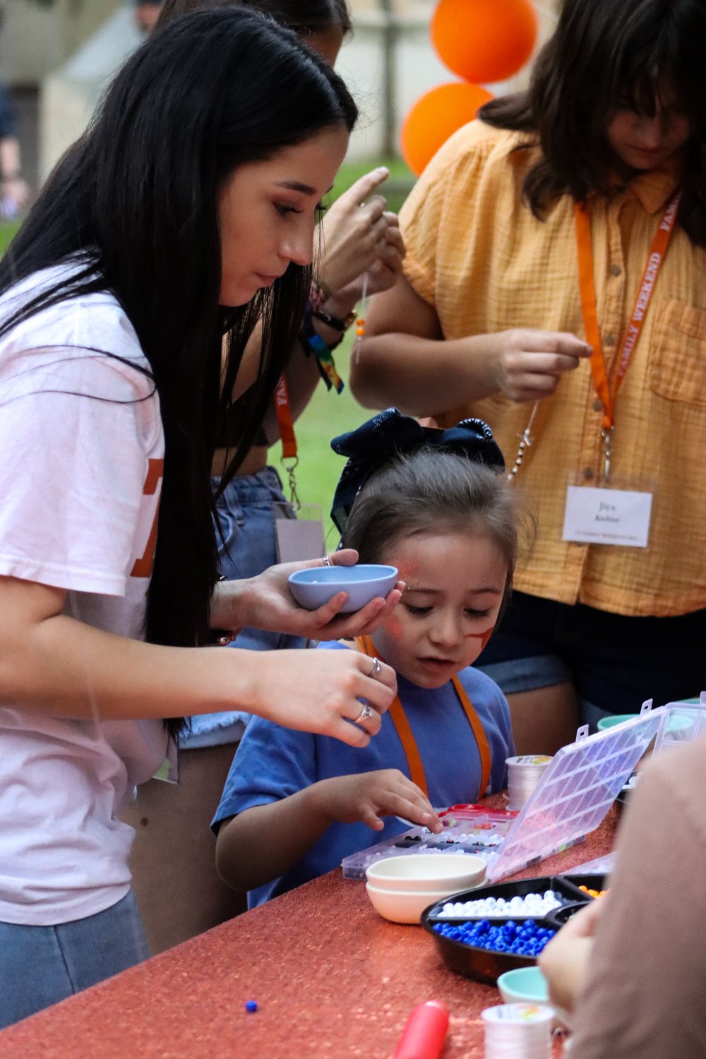  A family enjoys the bracelet-making station and picks out beads to make their jewelry.&nbsp; 