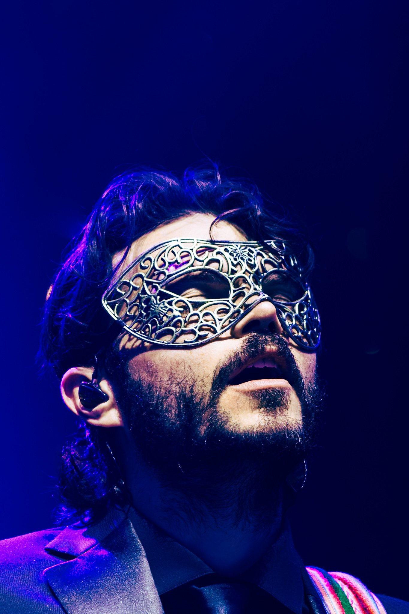 Goose steps onto the stage in hooded capes and masks beneath shimmering chandeliers.