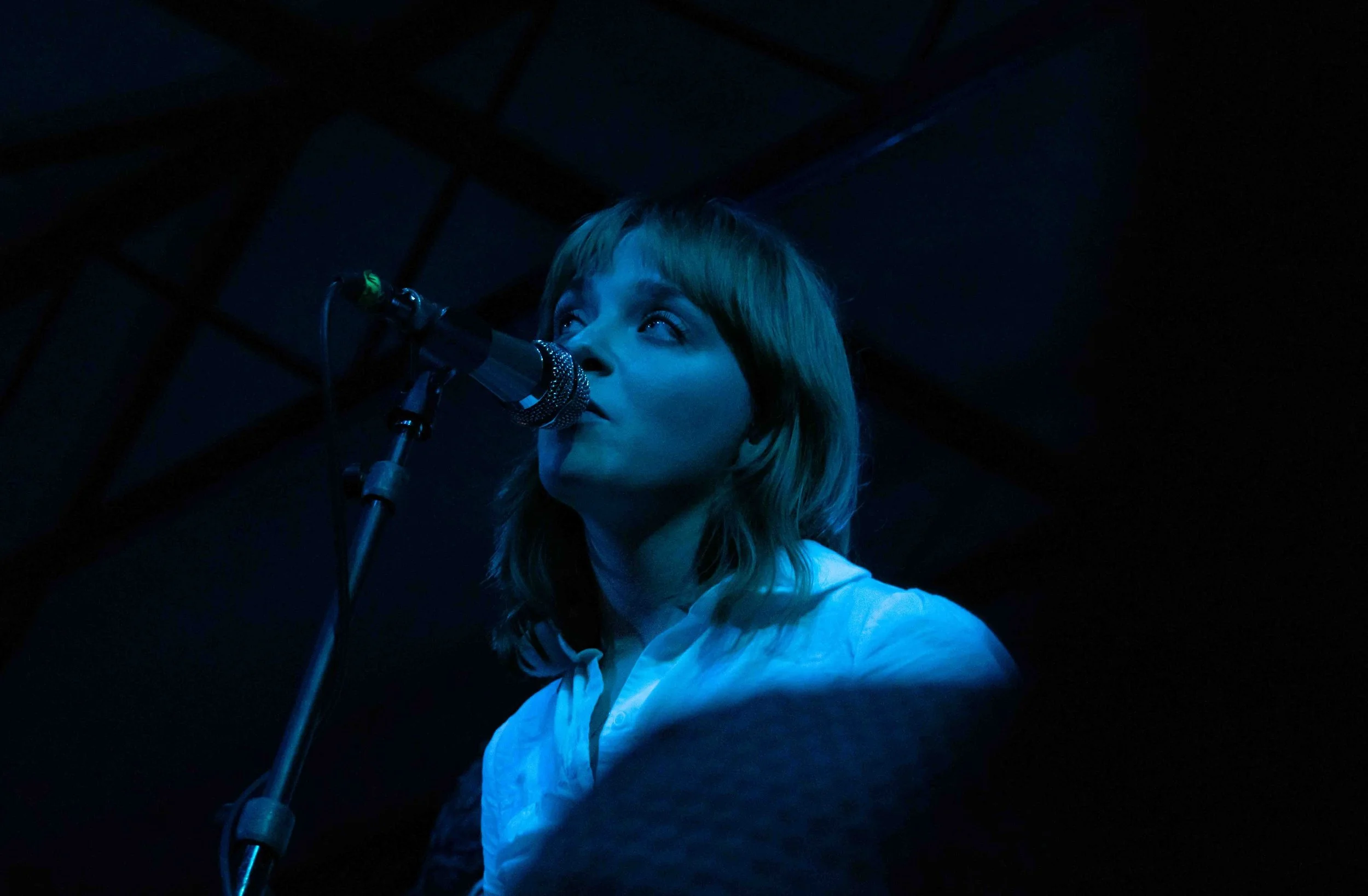  Smith looks off into the upper section of the crowd while singing “Little Birds” in moody blue lighting. 