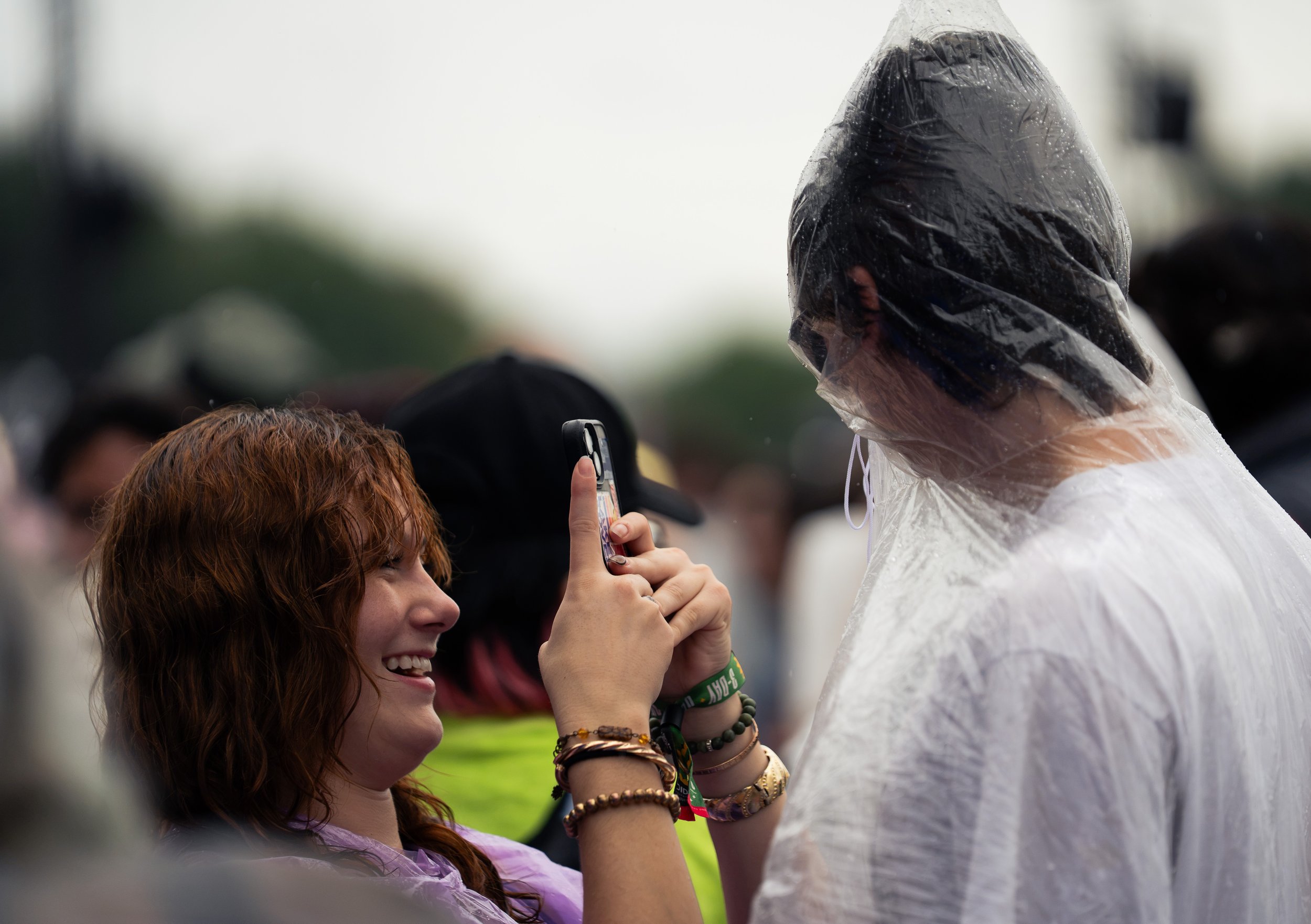  A girl takes a photo of her partner covered in a poncho while waiting for Grocery Bag’s set to begin. 