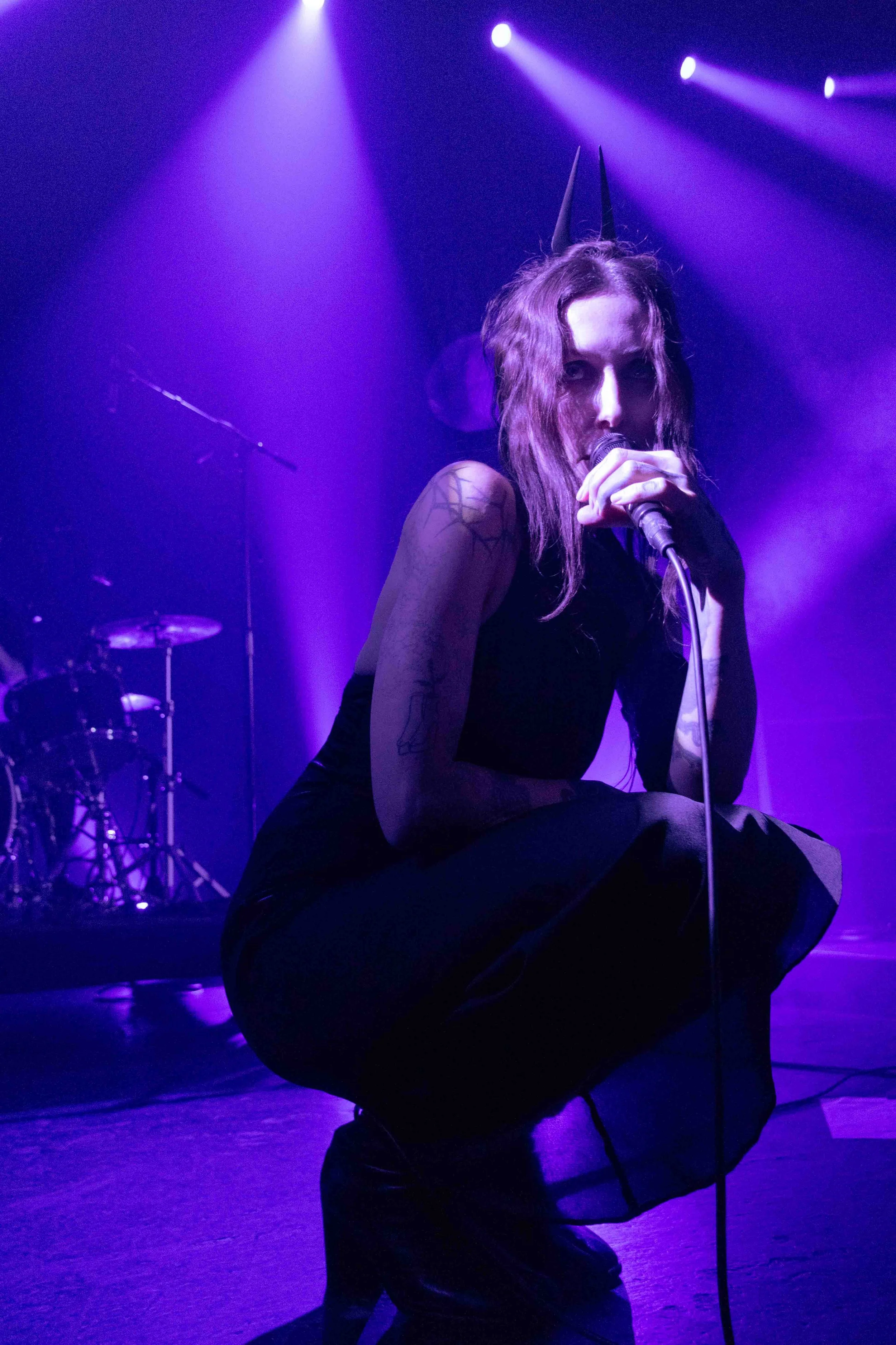  Wolfe crouches in front of the audience while performing the brooding song “Whispers In The Echo Chamber.”&nbsp; 