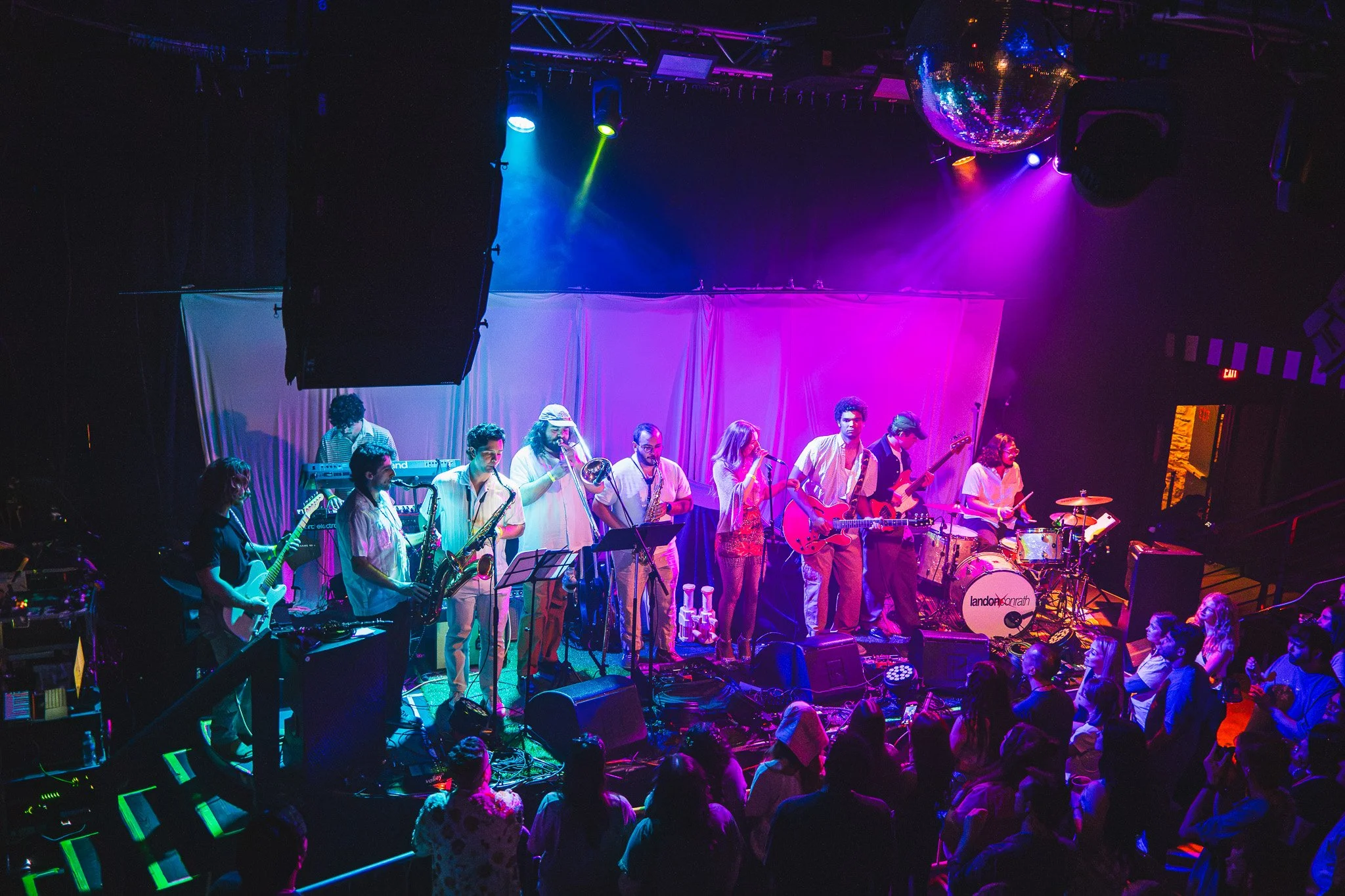  Saxophones, trombones, guitars,and a drum kit line the stage as Lynndigo sings her indie- popsongs. 