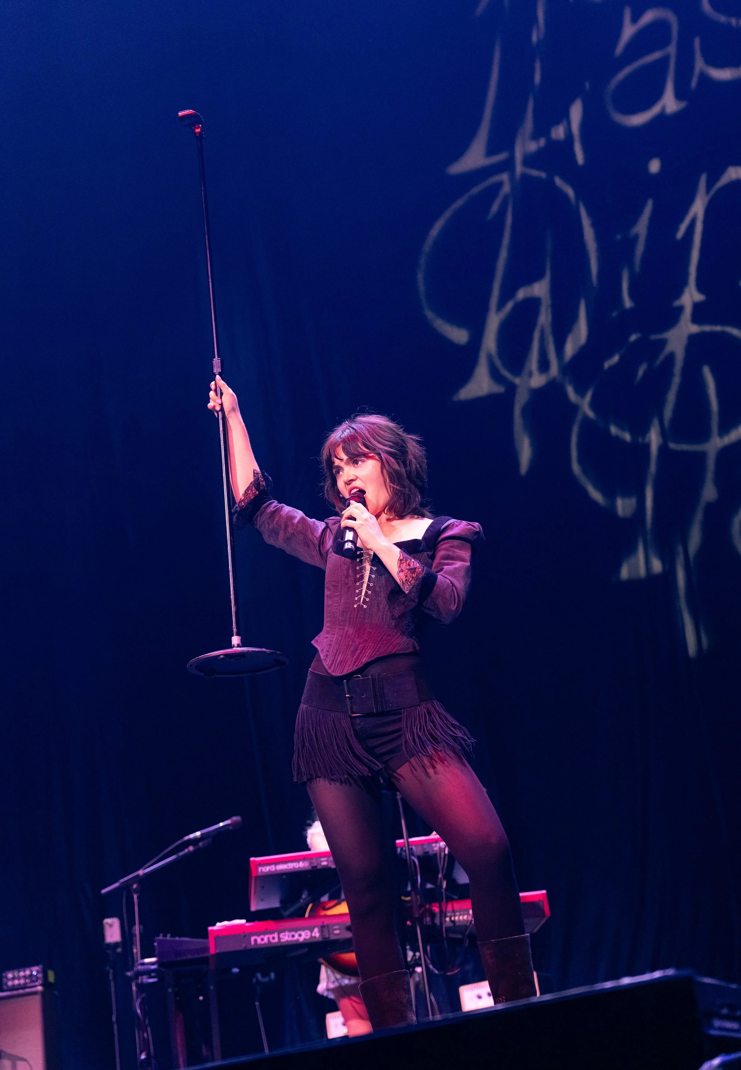  Morris holds up the mic stand while singing the post-chorus of “The Feminine Urge”: “Do you feel like a man when I can't talk back? / Do you want me or do you want control?" 