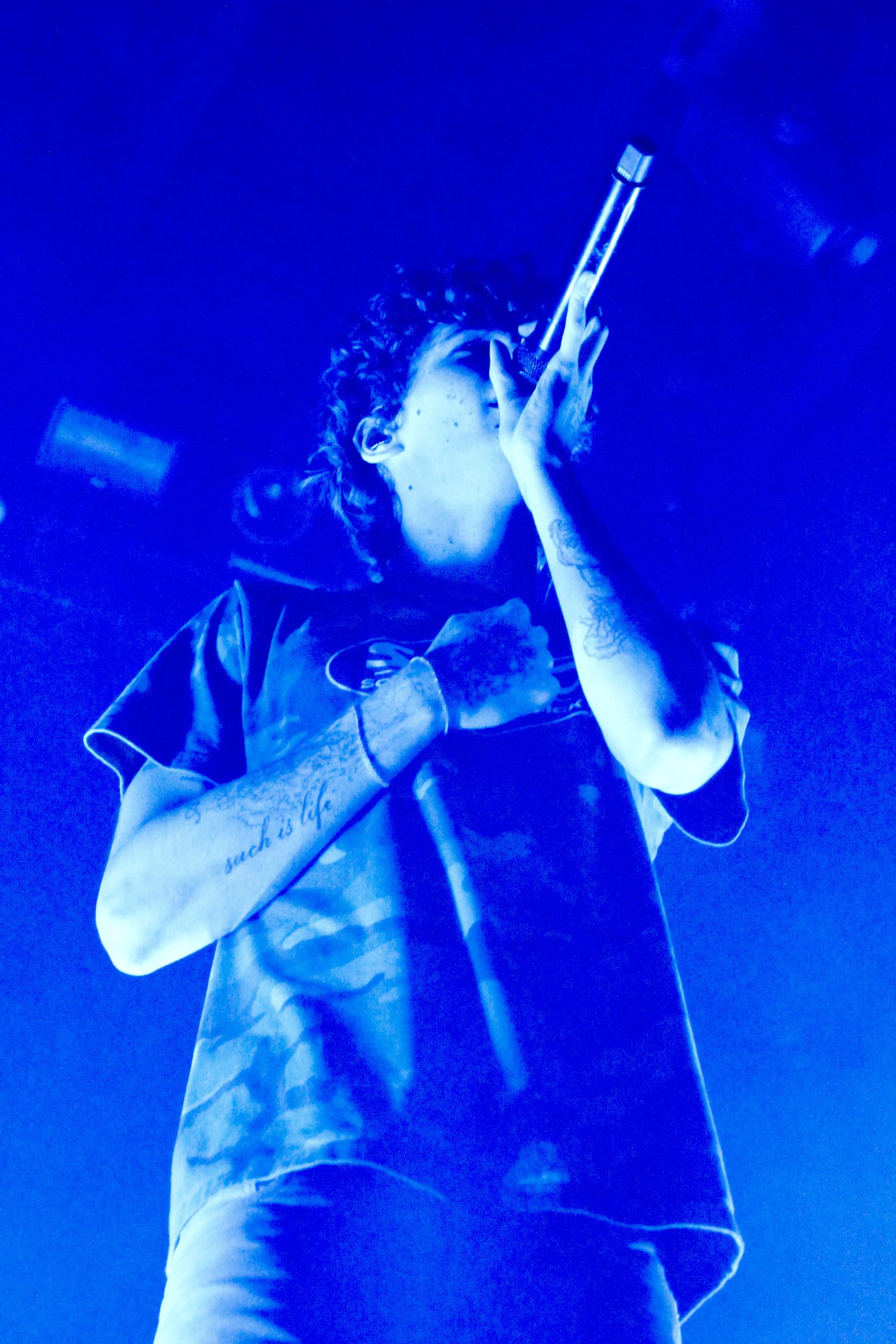  Stage lights illuminate glaive as he performs “Weston Super Mare”: “Would you come around? / I'm coming down / Baby, I'm coming down.” 