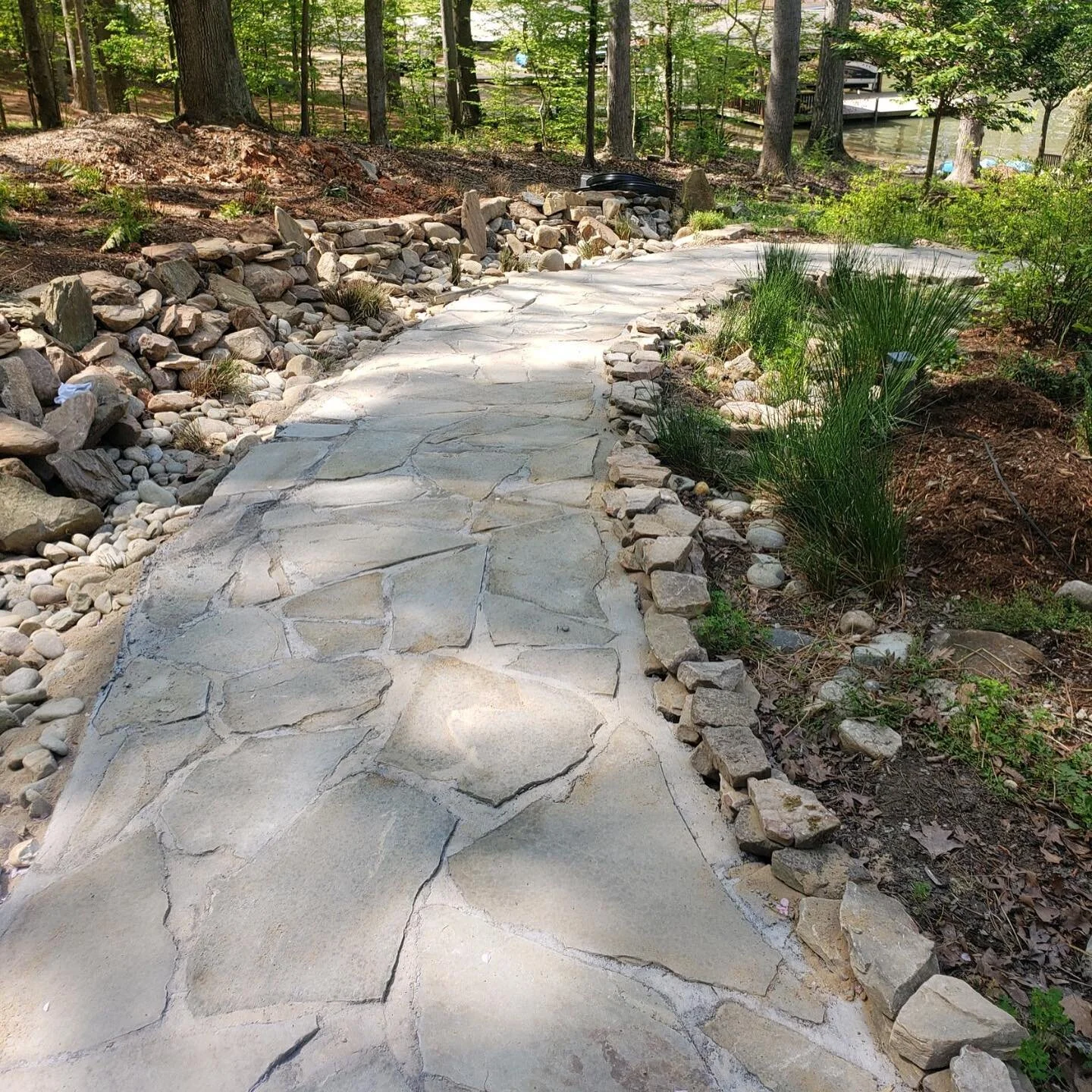The dry river bed drainage swale pairs well with our Pennsylvania blue flag stone walkway. Mortar in between the stones help lock in their position and direct runoff away from foot traffic. Social distancing the best way we know how 🌞