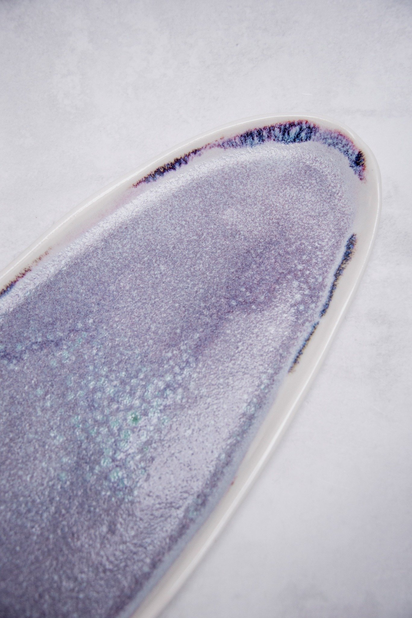 This is a  highly decorative glaze we call Nebula - it blooms into deep purples, shifting with thickness from lighter pinks to turquoise dotting and deep violets. Works beautifully on both porcelain and stoneware, producing rich cosmic tones and subt