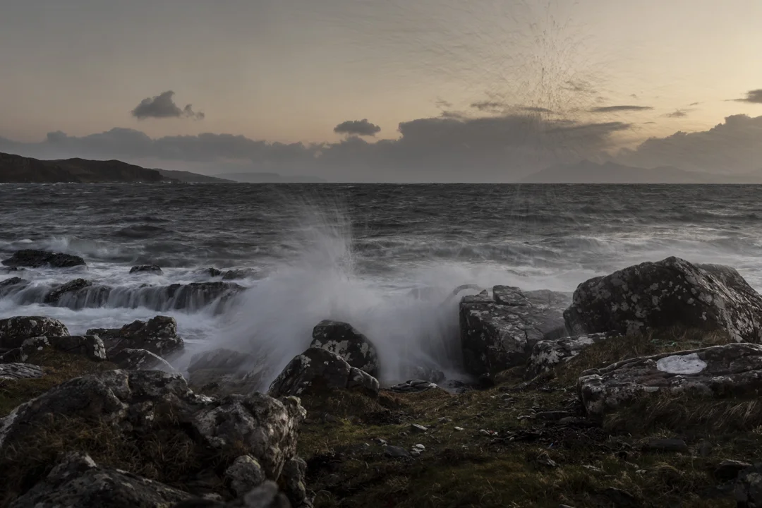 A stormy Tarskavaig Beach at sunset with waves crashing on the rocks