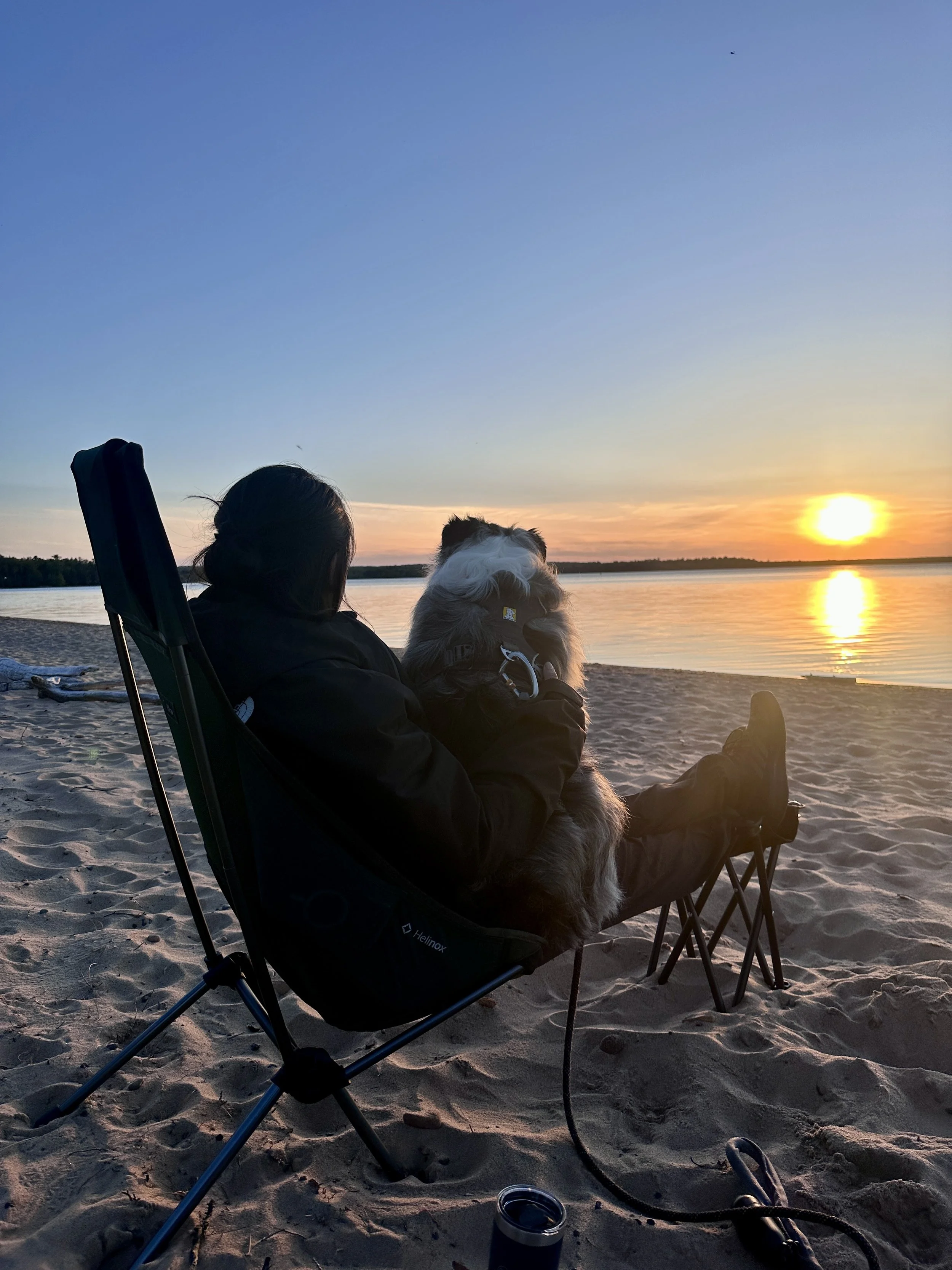 Woman and dog sitting in a camping chair on Lake Superior in Michigan's Upper Peninsula