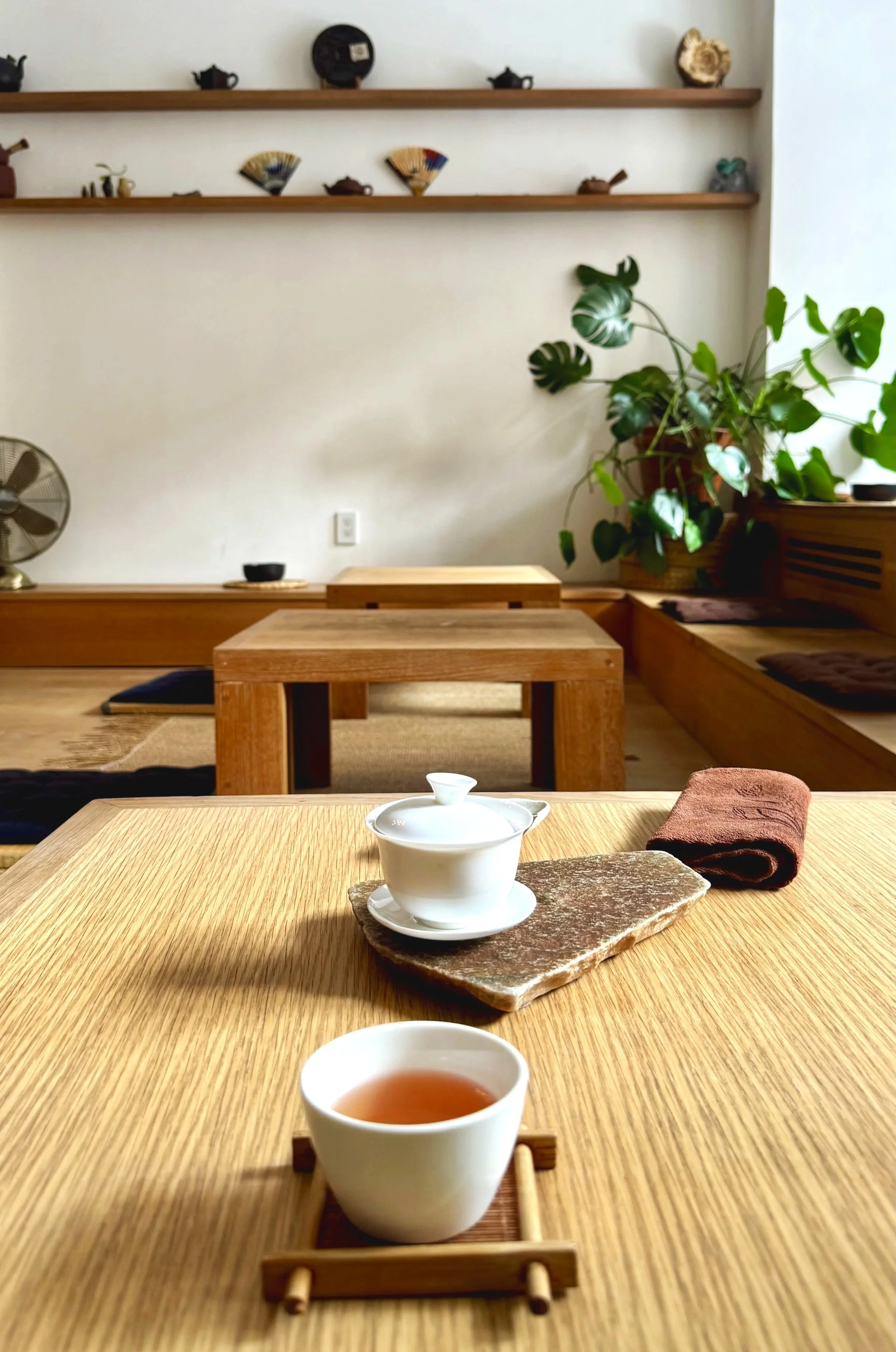 White ceramic gaiwan and tea cup on a wooden table inside the serene, minimalist interior of The Floating Mountain Tea House in New York City