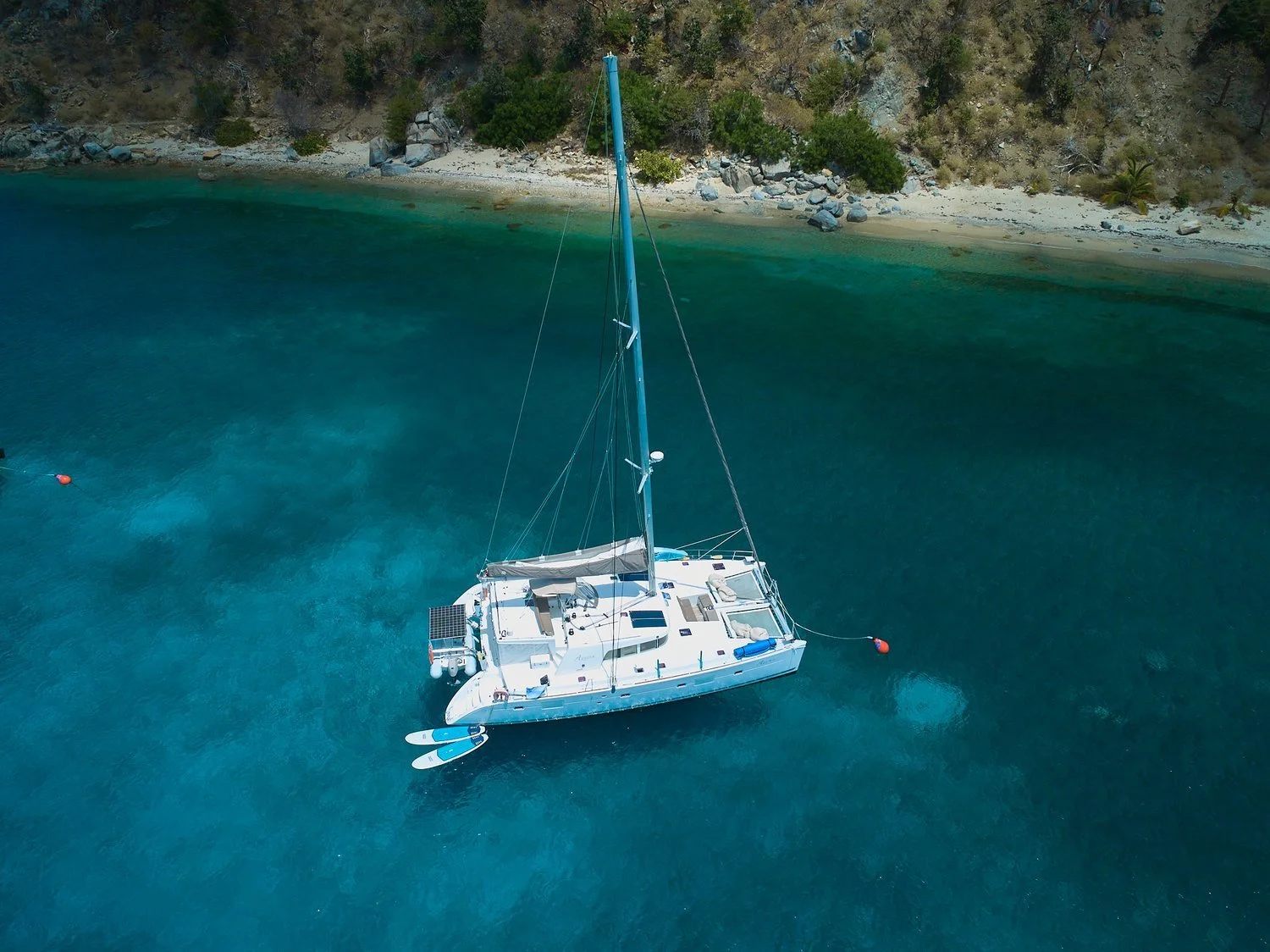Aerial view of a catamaran anchored in turquoise water near a beach