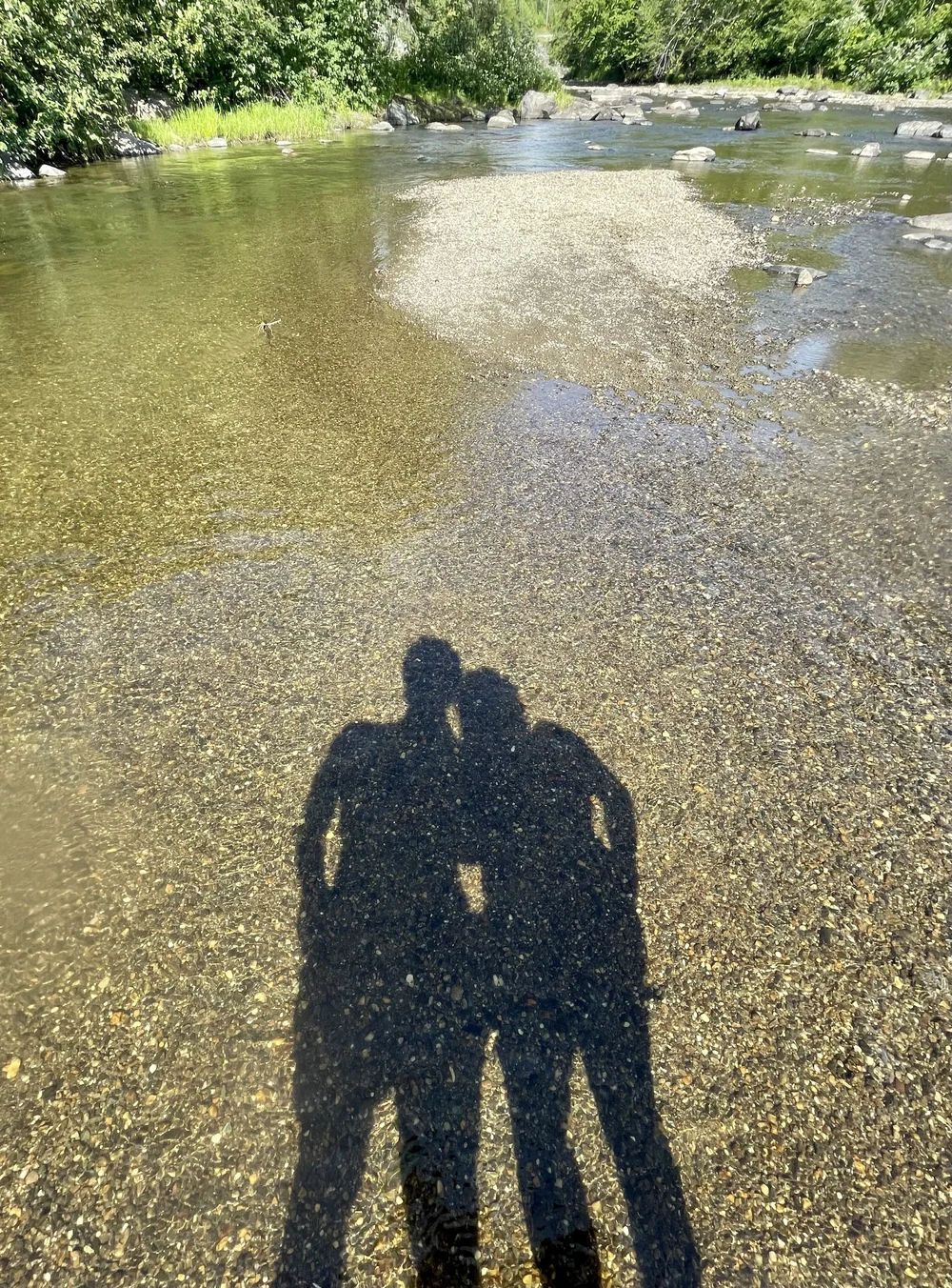 Couple's shadows against river water embracing 