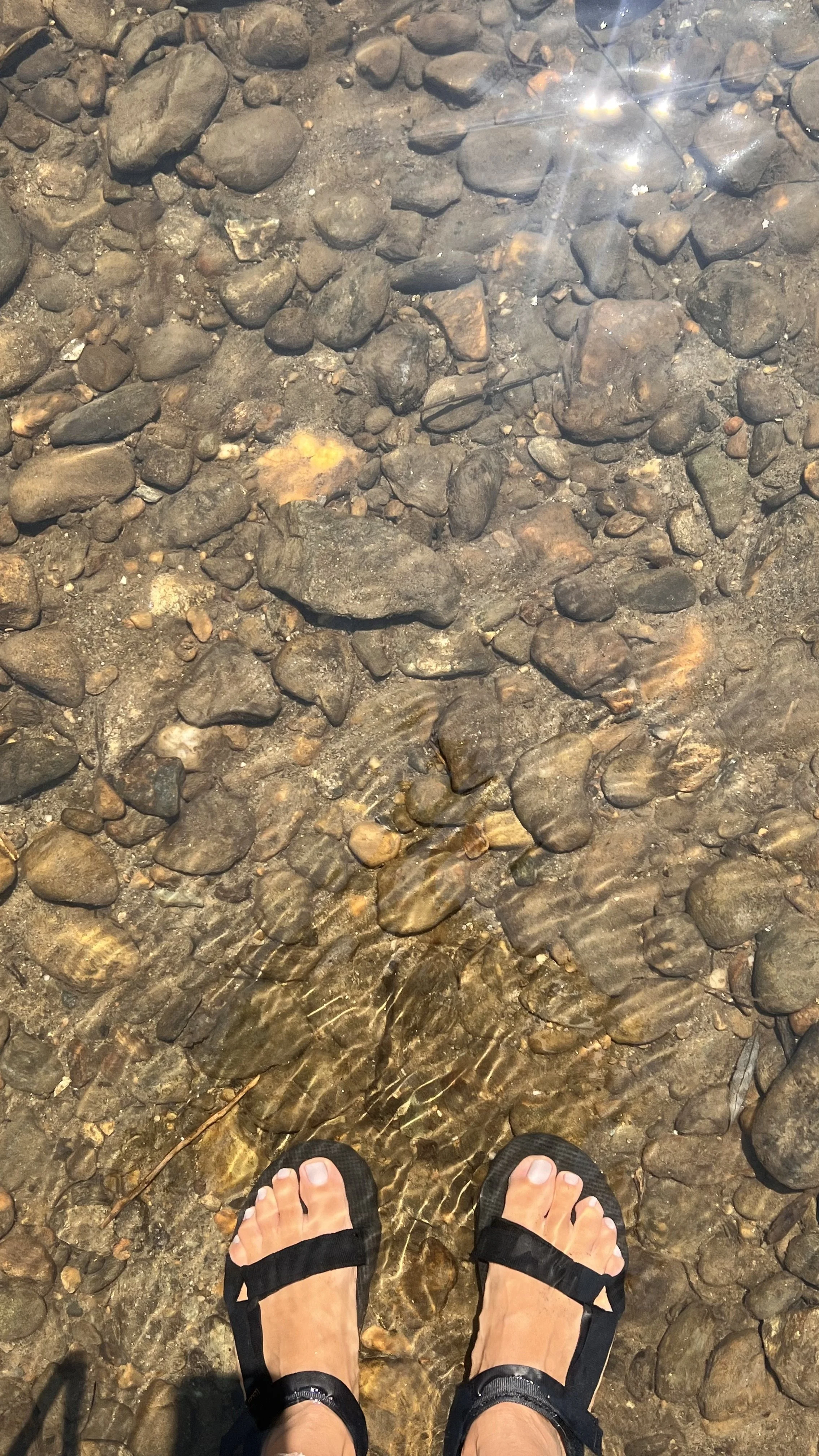 Woman's feet soaking in river water with rocks