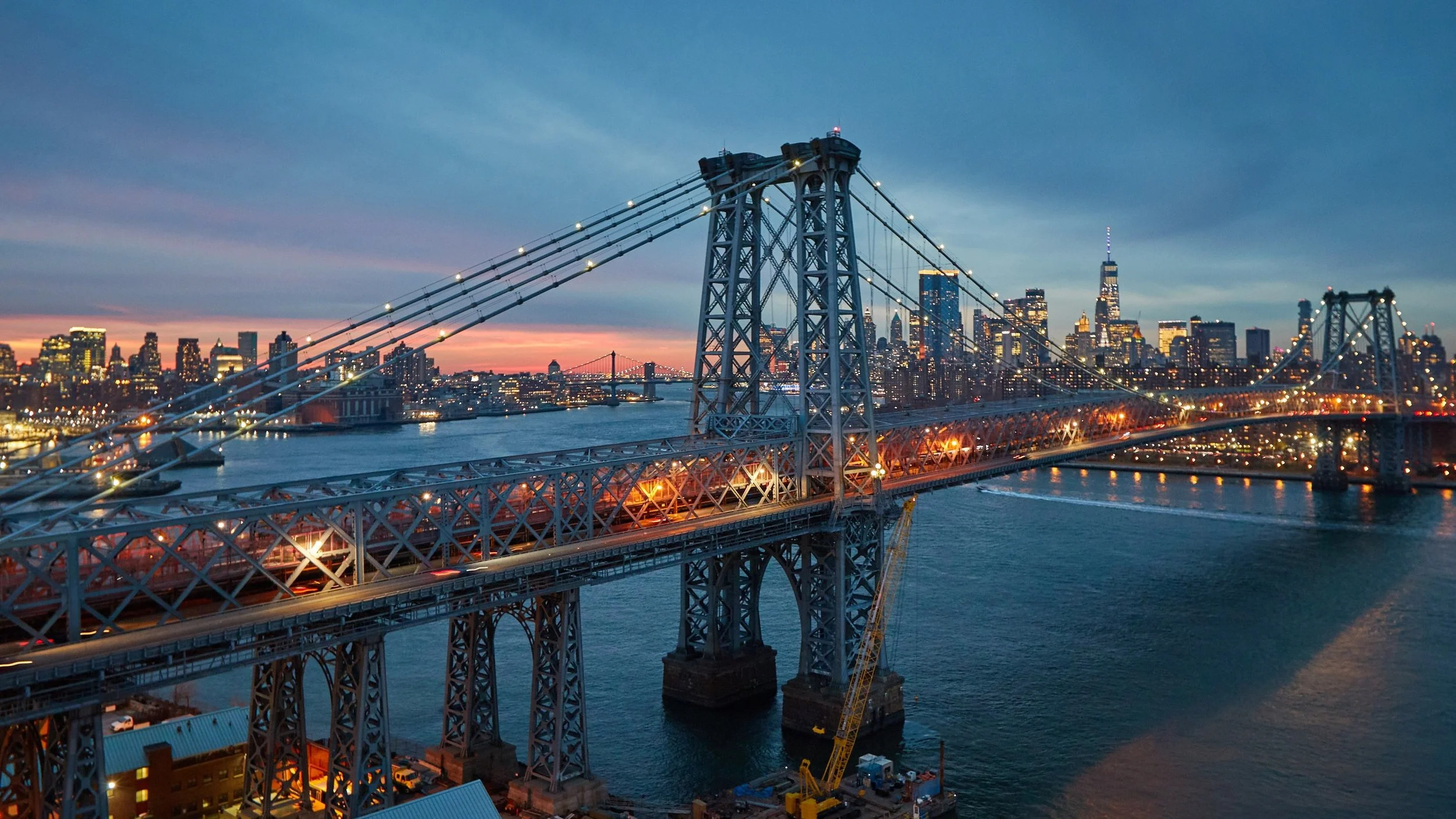 Williamsburg Bridge lit up at night with the Manhattan skyline in the background, Brooklyn, NY
