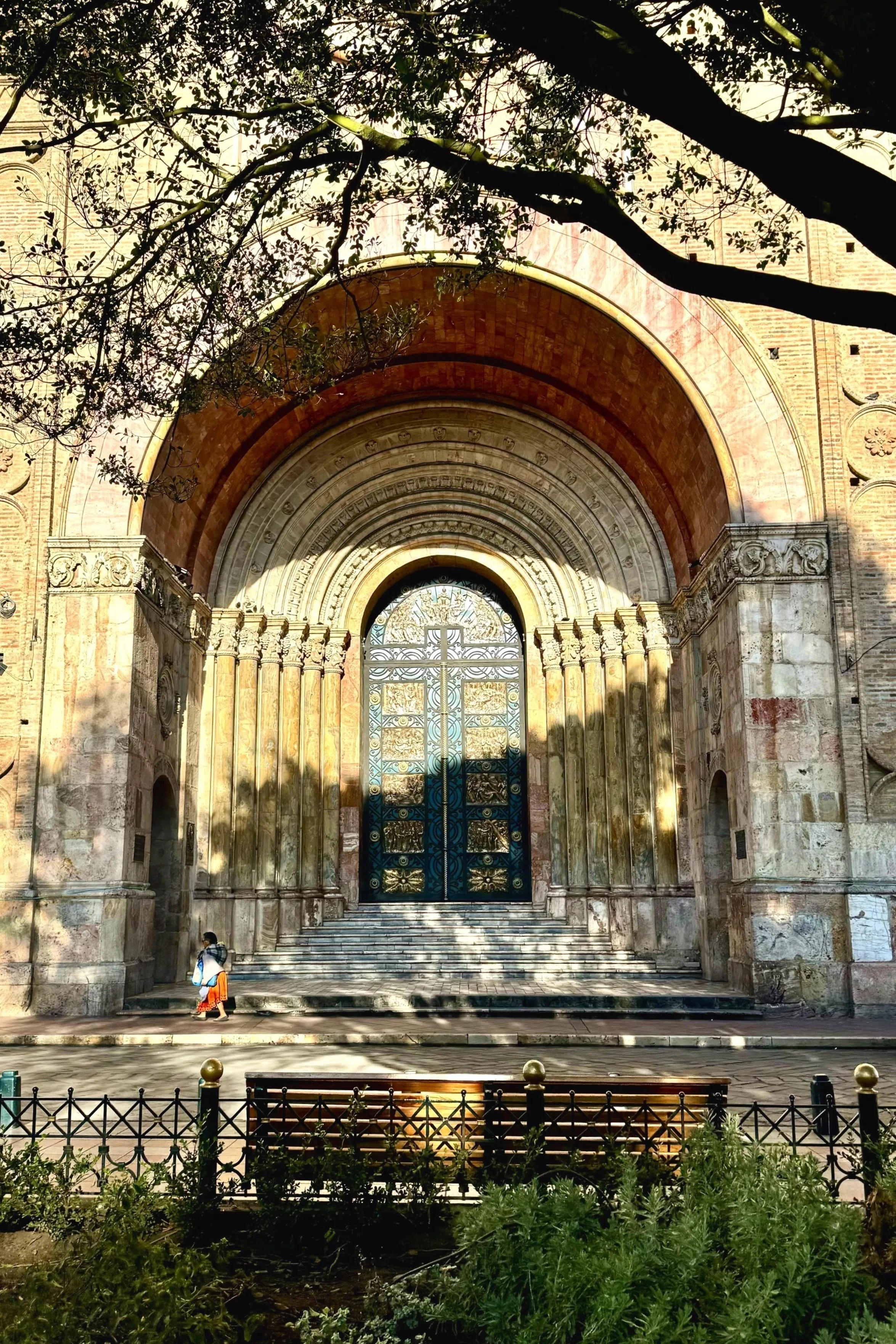 Grand arched cathedral entrance in Cuenca, Ecuador, framed by overhanging tree branches