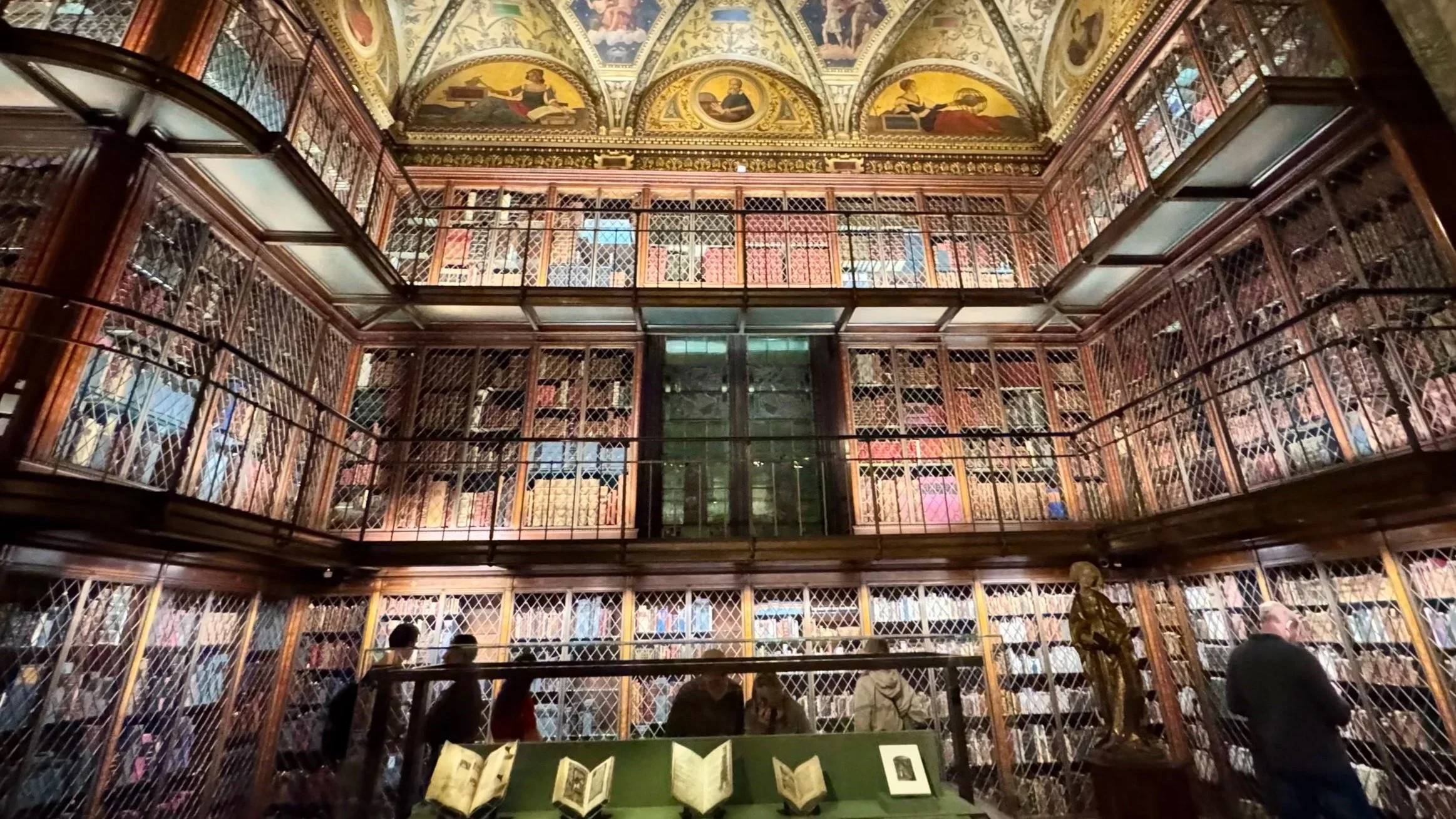 Interior of the Morgan Library & Museum, showing the historic three-story bookshelves and painted ceiling in New York City
