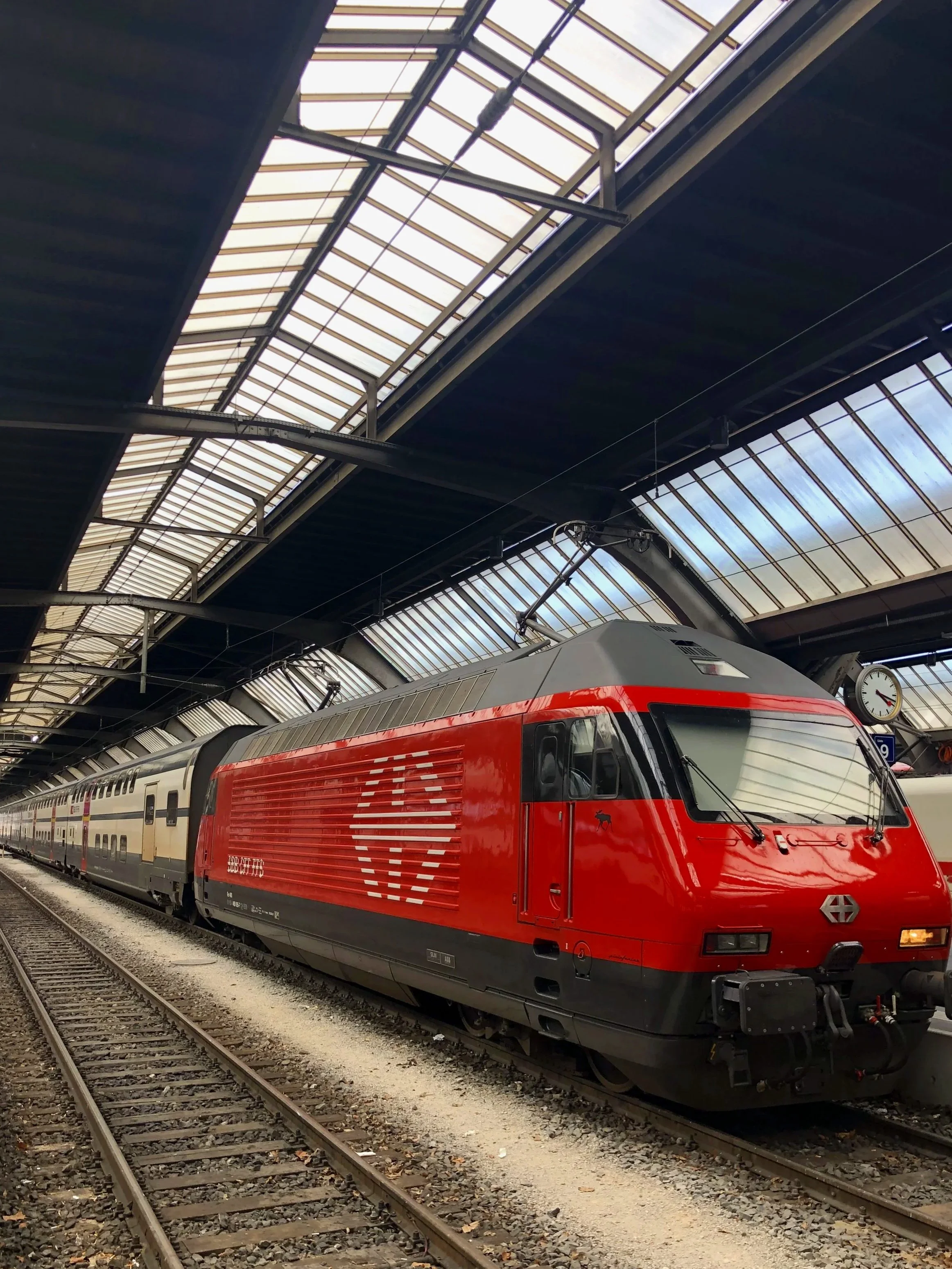 Red Swiss Federal Railways locomotive at Zurich Hauptbahnhof train station under a glass and steel roofRed Swiss Federal Railways locomotive at Zurich Hauptbahnhof train station under a glass and steel roof