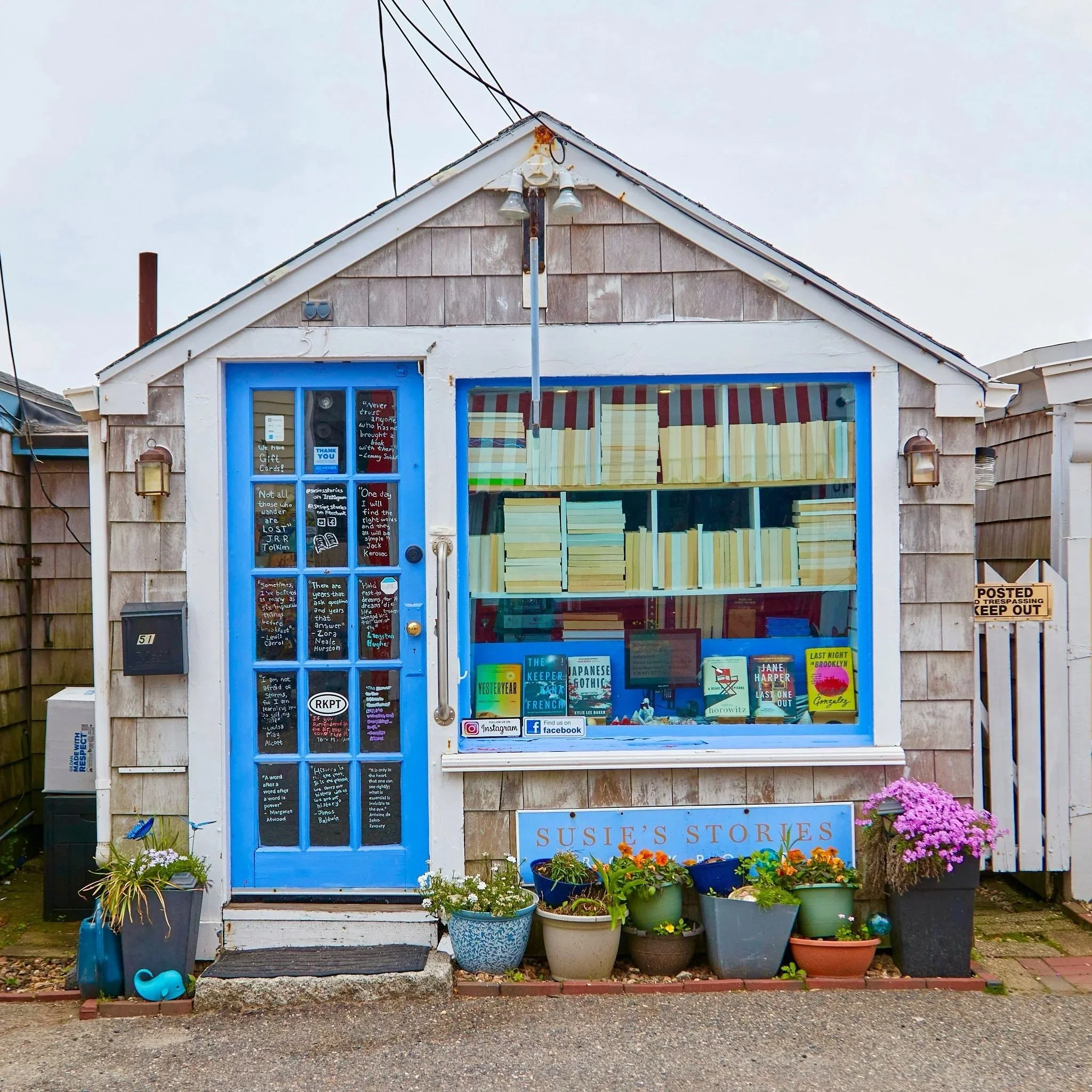 Susie's Stories bookshop on Bearskin Neck in Rockport, Massachusetts — a small shingled cottage with a blue door and literary quotes on the windows.