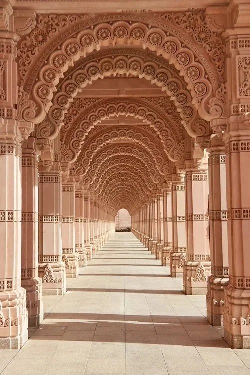 Ornately carved pink stone archway corridor at BAPS Swaminarayan Akshardham temple in Robbinsville, New Jersey