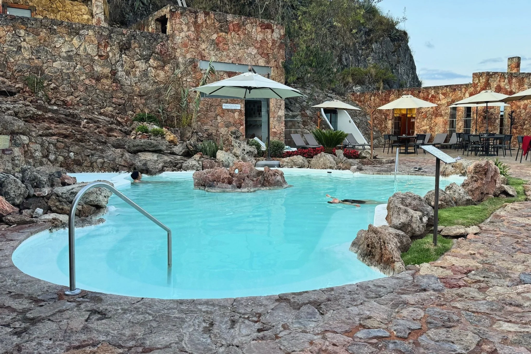 urquoise thermal pool at Piedra de Agua near Cuenca, Ecuador, with guests soaking among natural rock formations
