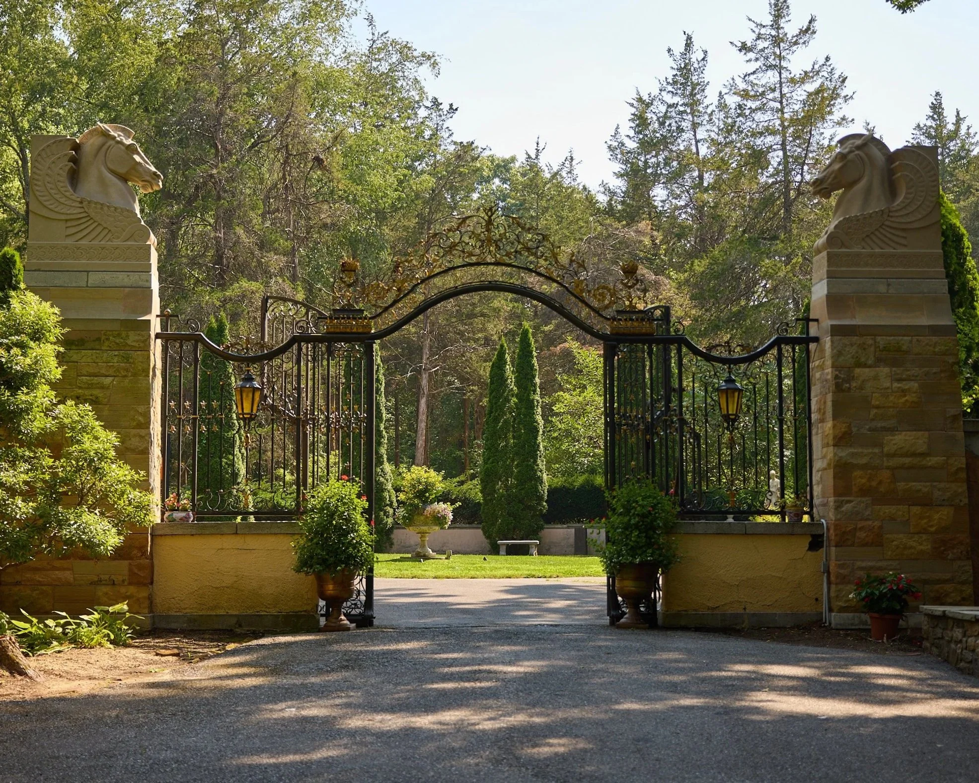 A wrought-iron garden archway framing a tree-lined path at Caramoor in Katonah, NY.