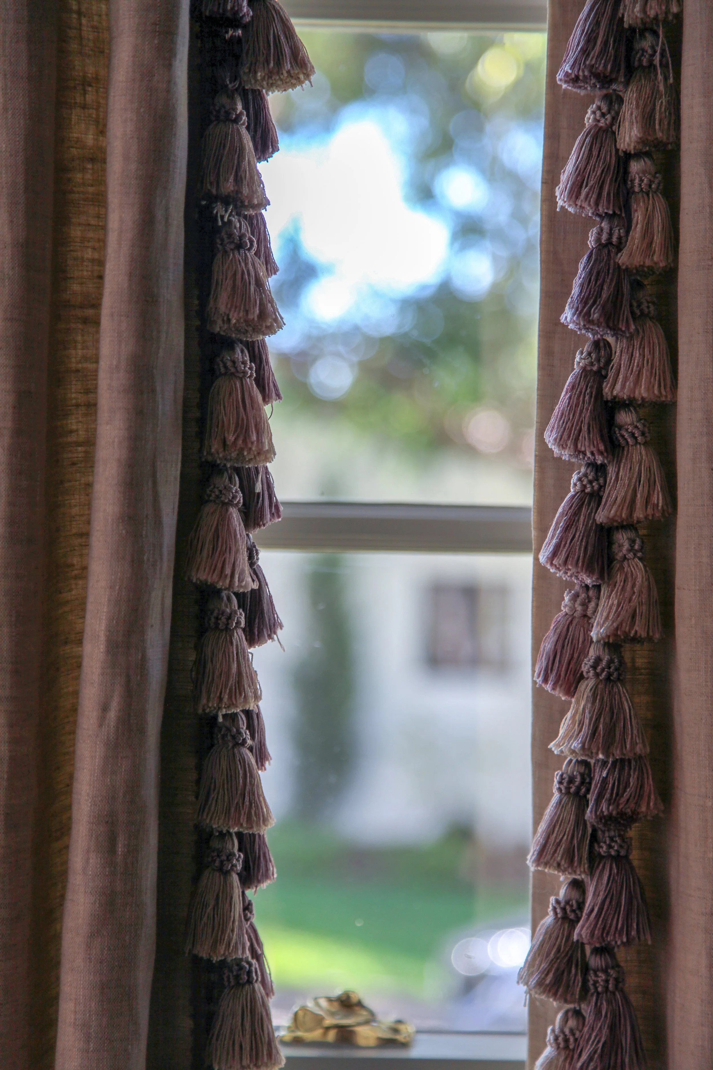 Here purple linen drapes are fringed with tassels in varying shades of purple.