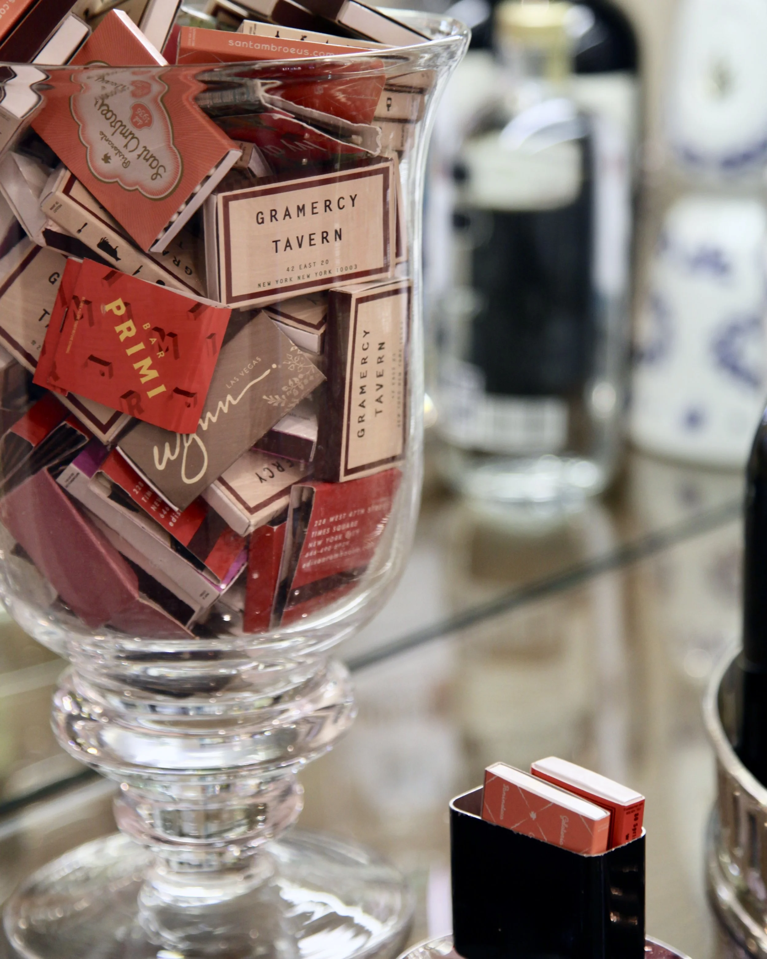 Matchbooks on display in a bar and a vintage matchbook holder to the right.