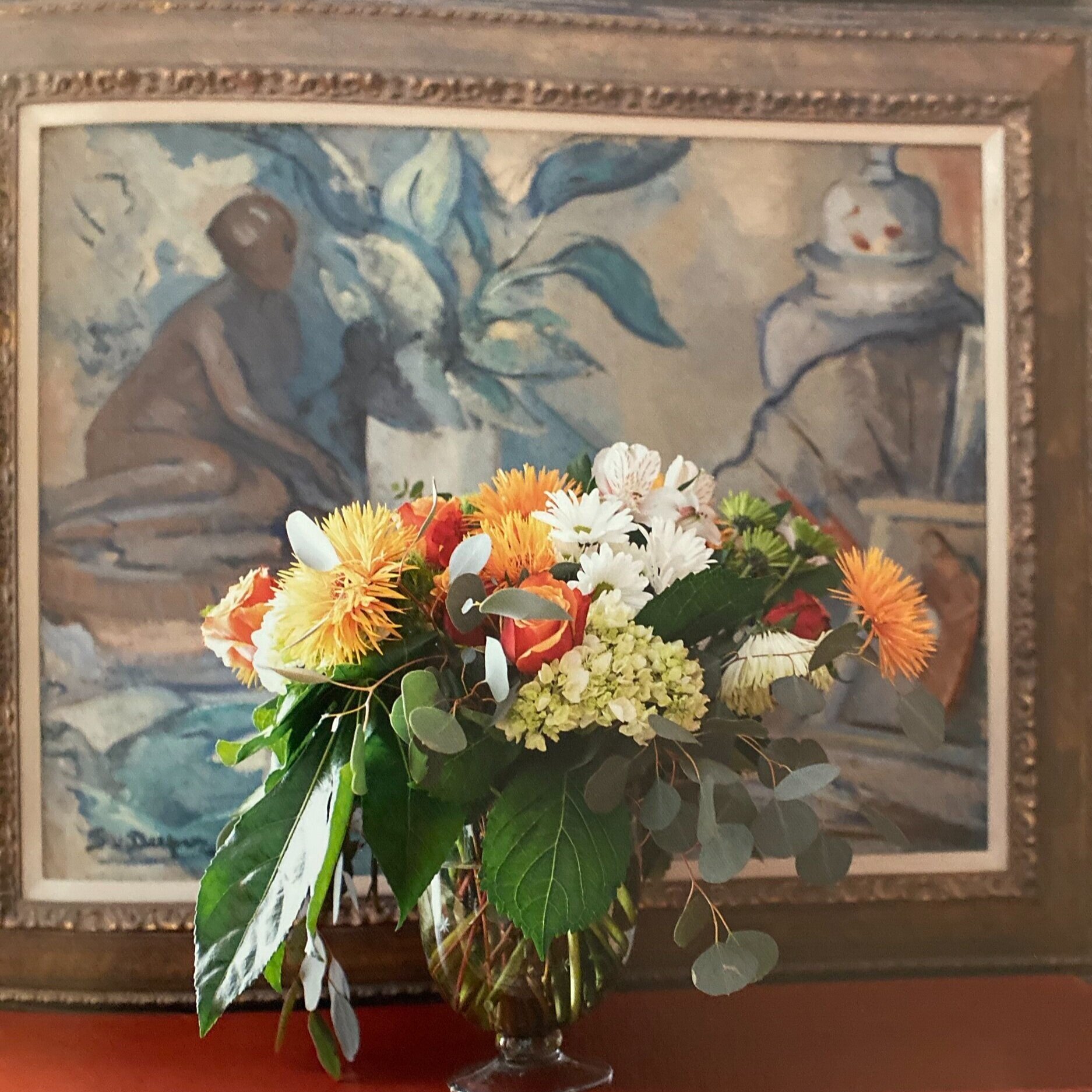  The hues of the flower arrangement draw the focus in with a muted oil painting behind. 
