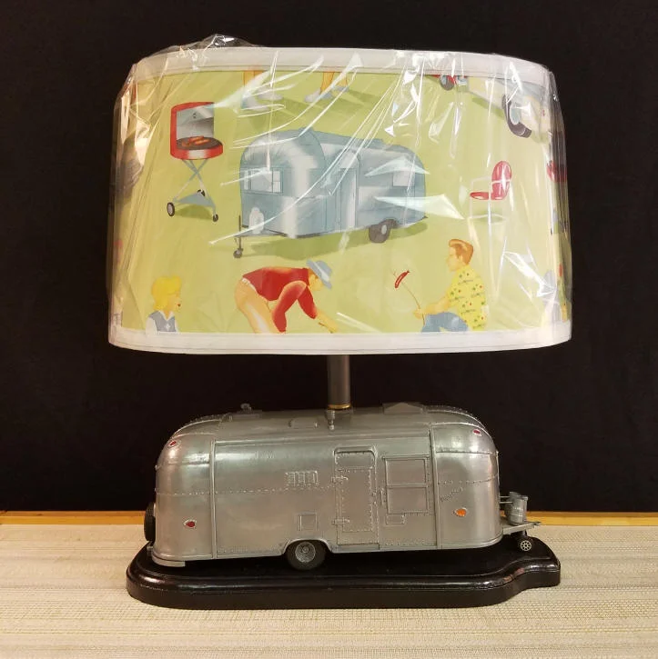 Die-Cast Airstream "Flying Cloud" Camper Lamp This die-cast Airstream RV / Camper is a retired piece that was sold by Pottery Barn. We have transformed it into this must-have lamp for any camping enthusiast. Since we make all of the lampshades we sell, we purchased this reproduction vintage camping themed fabric for the shade. Buyer may request traditional shade, if desired. It stands 15" tall, including the lampshade & is 14" wide. Great size for any location, maybe even your Airstream Travel Trailer. $250.00, plus shipping