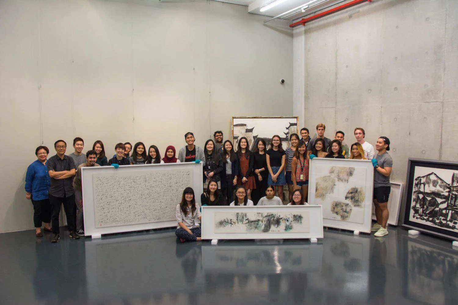 Exhibition team and students of SMU-X Arts and Cultural Management course on Exhibitions and Curating viewing artworks at Fine Art Storage Services, Singapore.