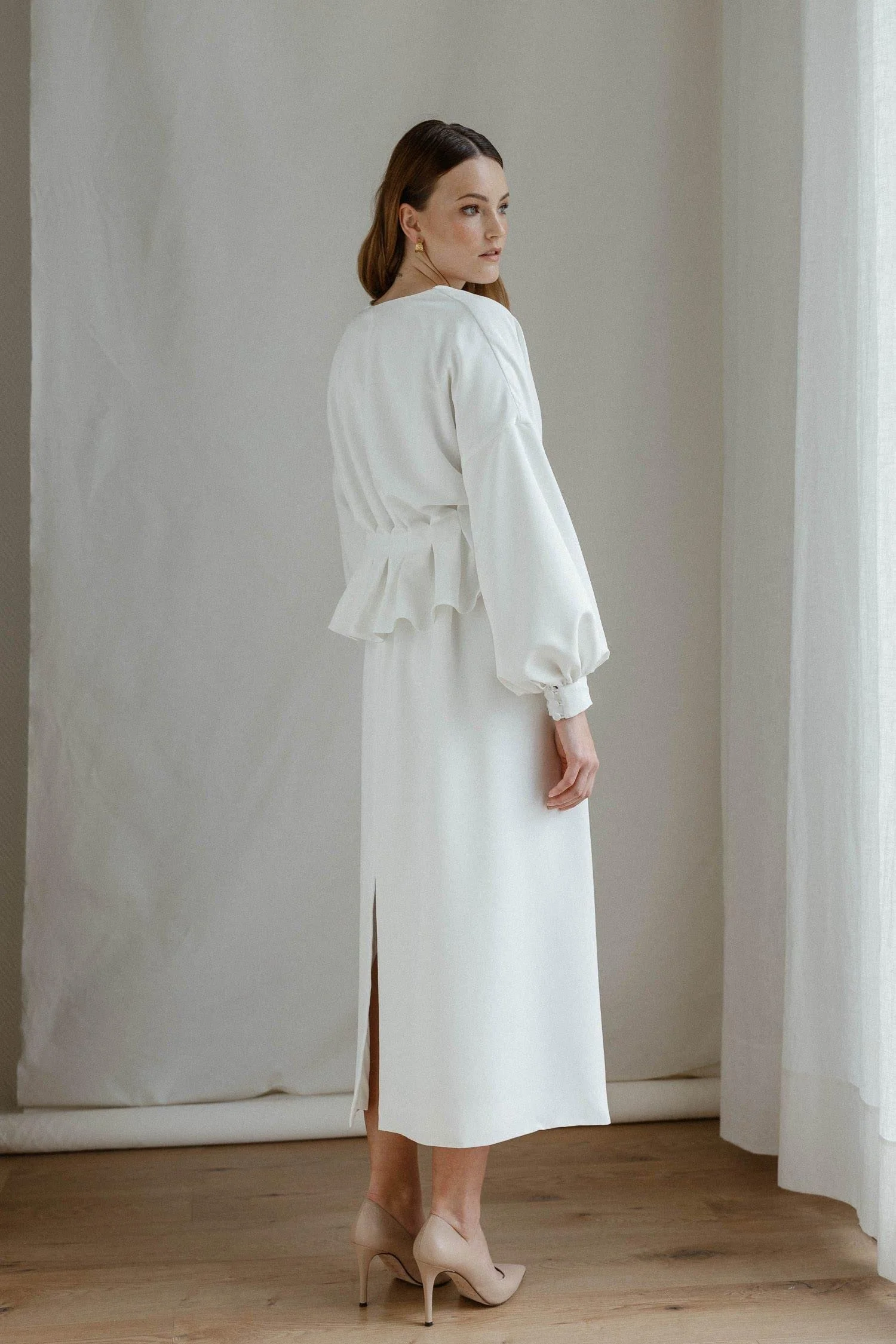 Valkoinen Agatha-hääasu, jossa on napitettava yläosa ja suora hame. Hameen halkion voi sijoittaa vapaasti eteen, taakse tai sivulle oman tyylin mukaan.