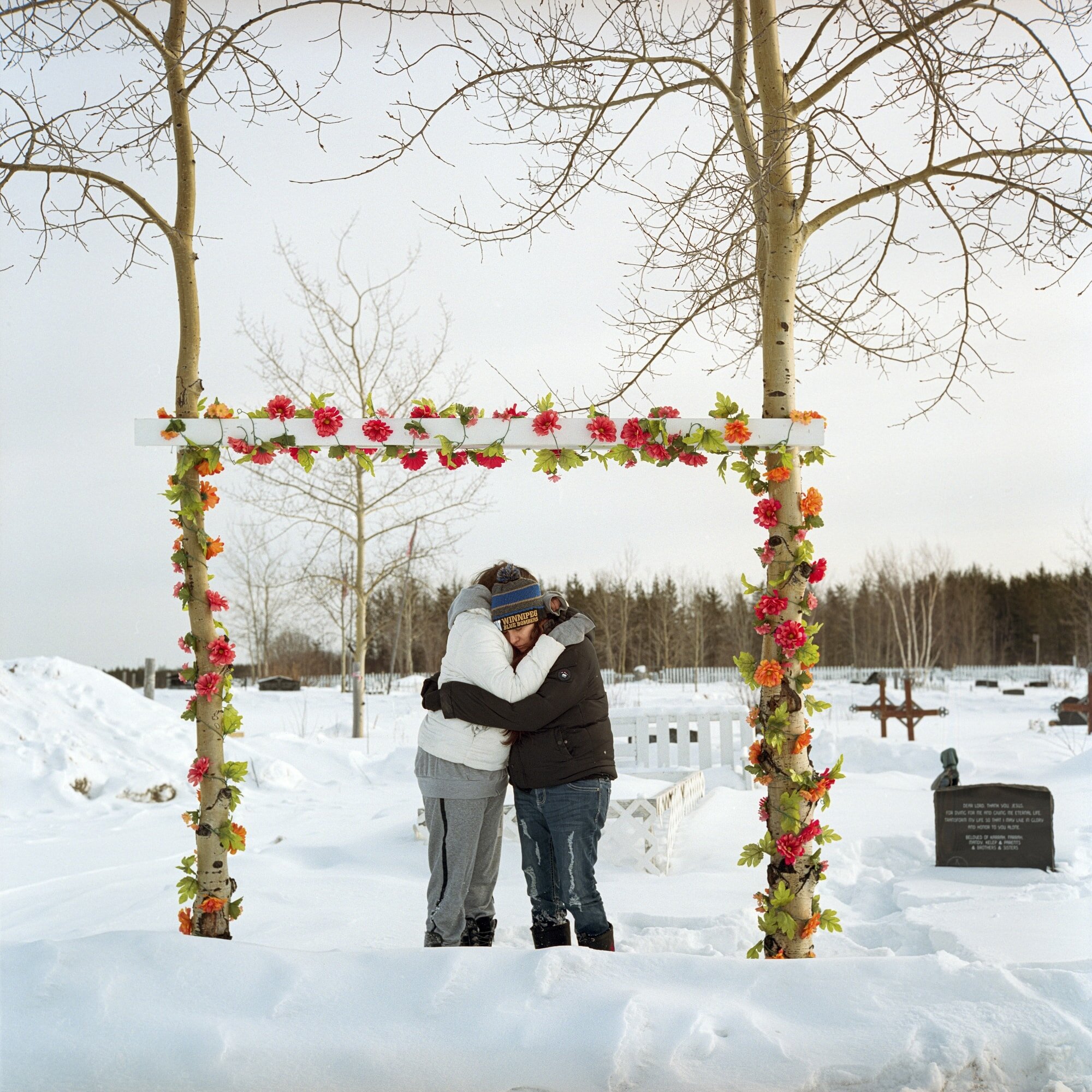 Kara Blacksmith, left, and her twin sister, Fara, embrace while visiting the grave of their late father, Abrose Thomas Ross. Ross died in 2015 after falling through ice while driving an ATV in the community of Cross Lake, home to the Pimicikamak Cre…