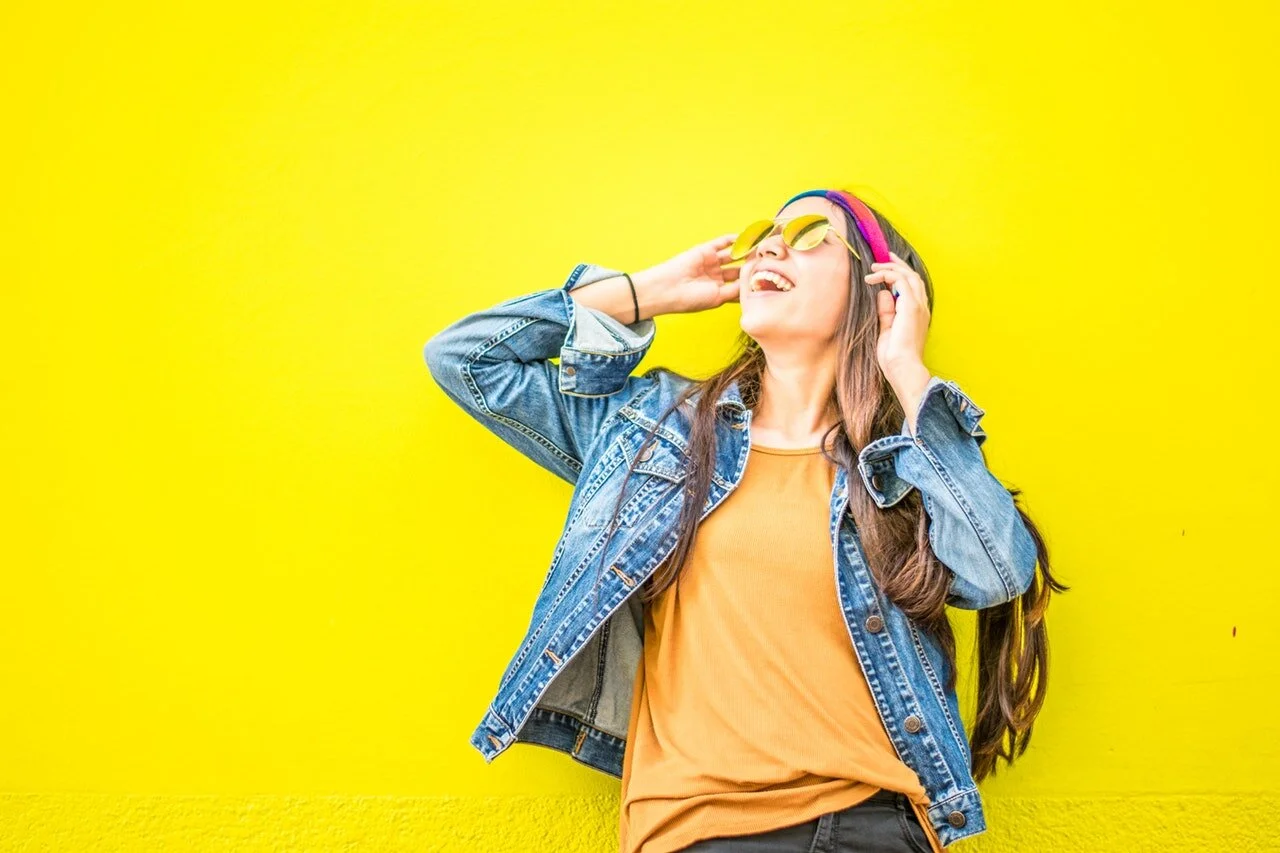 smiling-woman-looking-upright-standing-against-yellow-wall-1536619.jpg