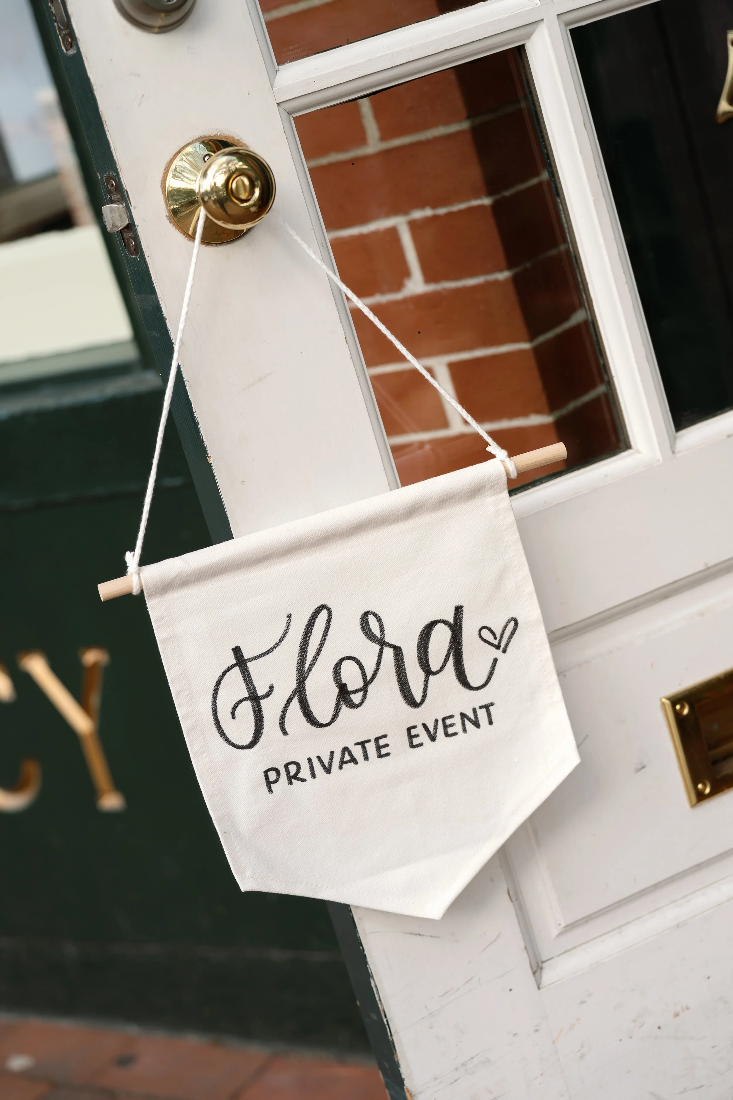 Close-up of a door with a gold doorknob and a sign hanging from a rope that reads 'Closed Private Event' with a small heart symbol.