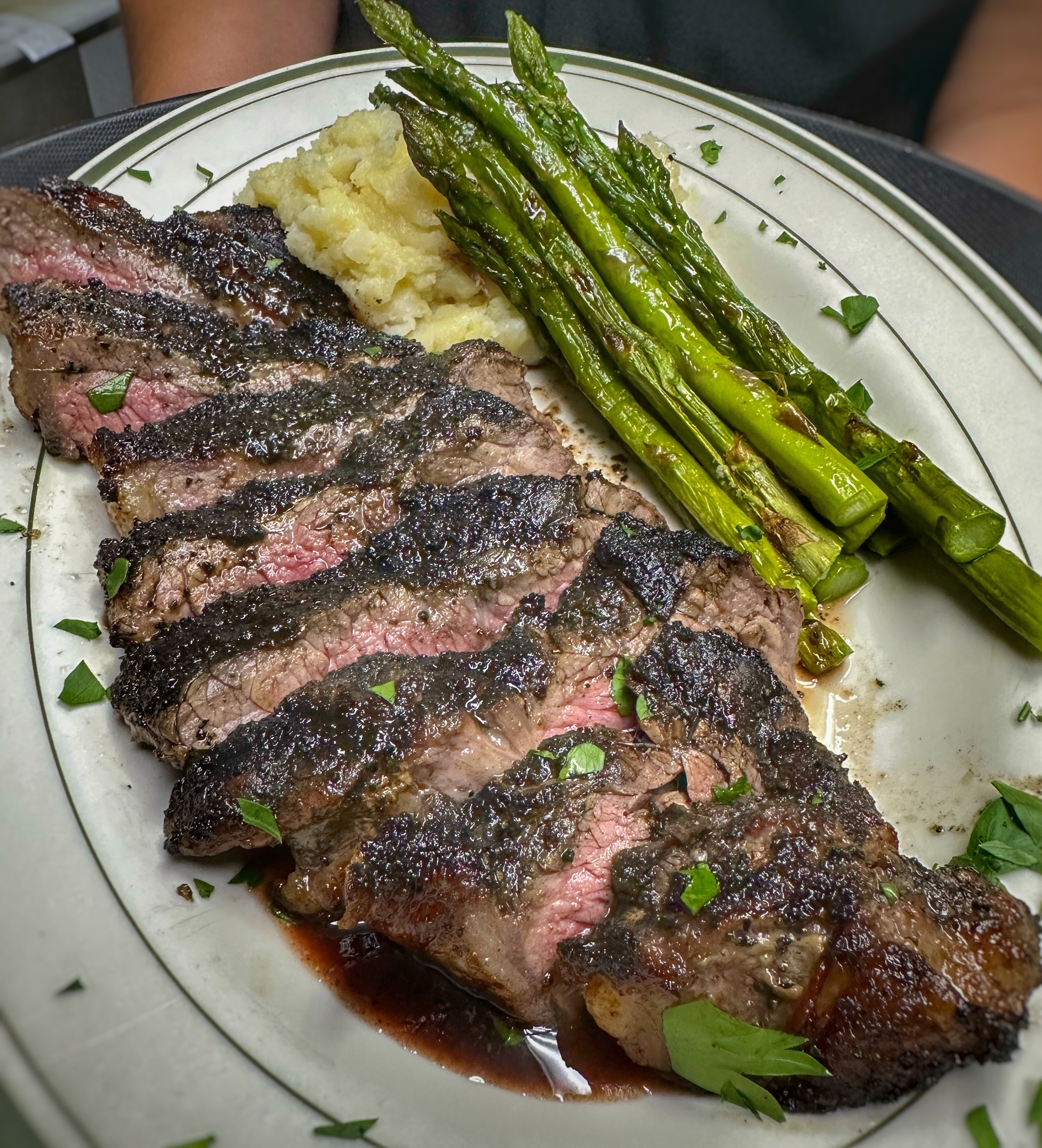 Grilled NY Cut Sirloin Steak at John & Molly's Tavern in Eastampton, NJ – thick, juicy 14–15 oz cut sliced into strips, charred crust with pink medium-rare center, drizzled in rich au jus or herb sauce, with garlic mashed potatoes and asparagus