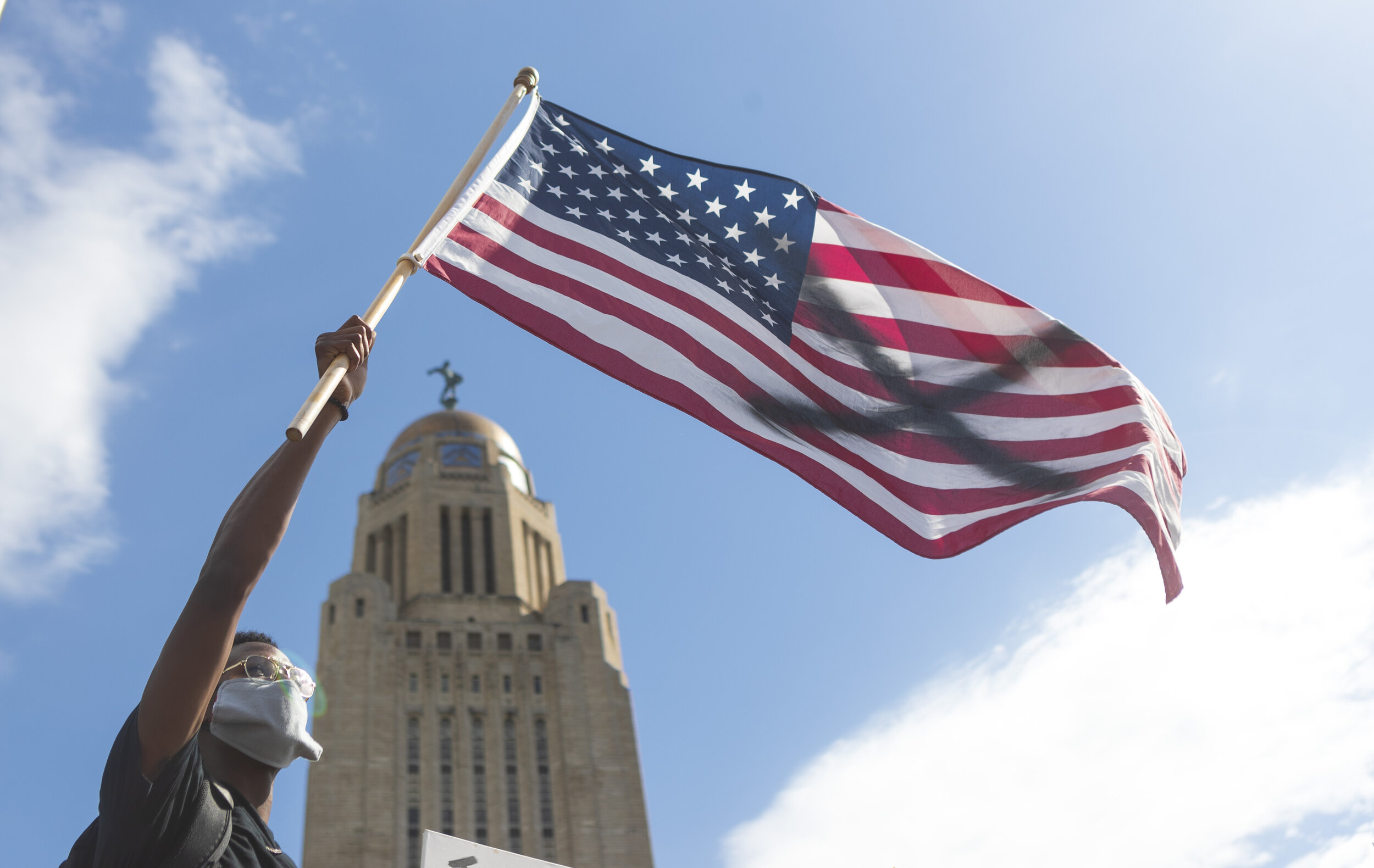  Temi Onayemi waves an American flag with an"X" painted on it in protest during a protest against police violence on Sunday, May 31, 2020, in the Lincoln Mall.  The Protest was one of the most attended protests in Nebraska history with thousands in a