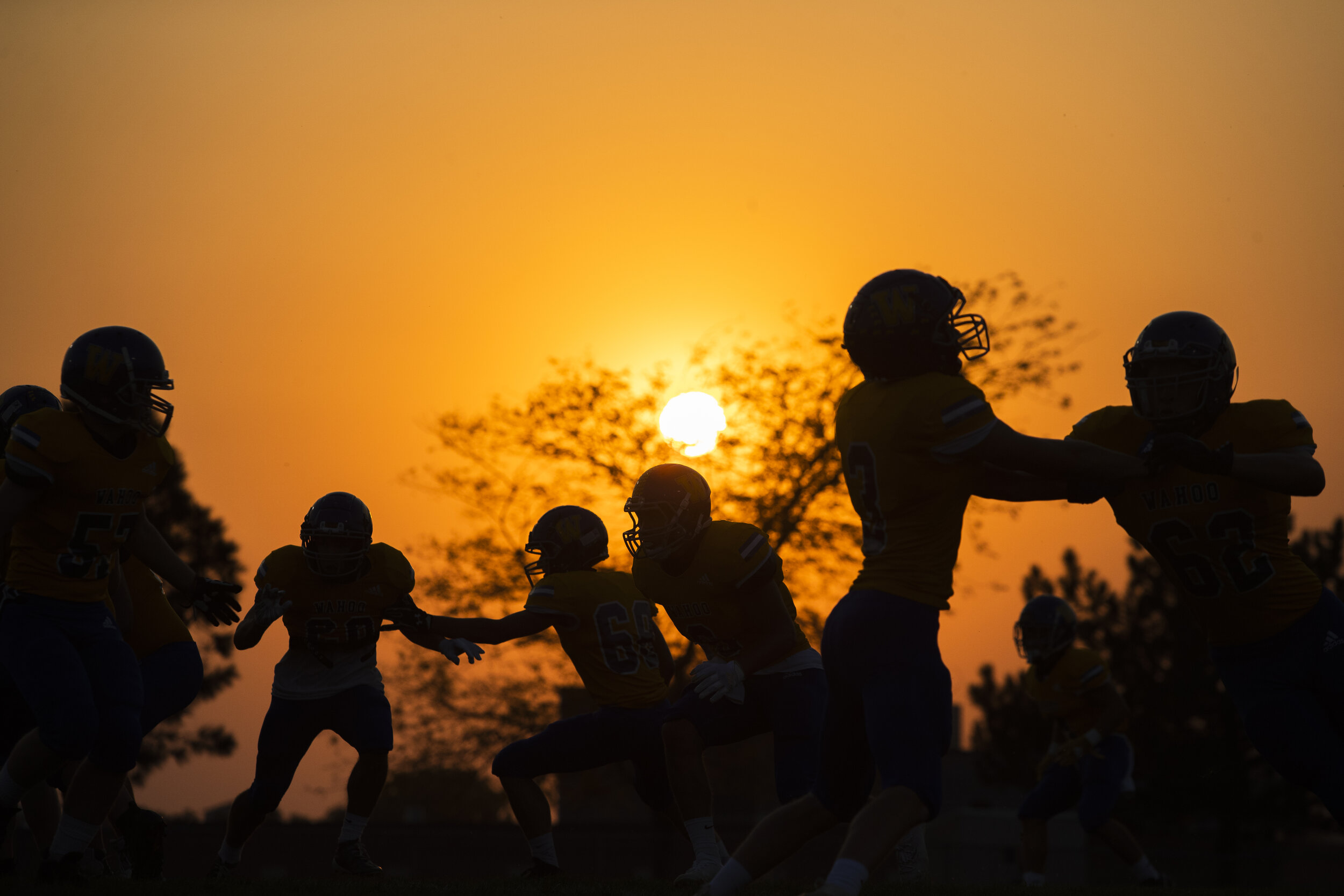  Wahoo players warm up as the sun sets behind them before they face off against Ashland-Greenwood at Wahoo High School on Friday, October 9, 2020, in Wahoo, Nebraska.  JOURNAL STAR, Kenneth Ferriera 