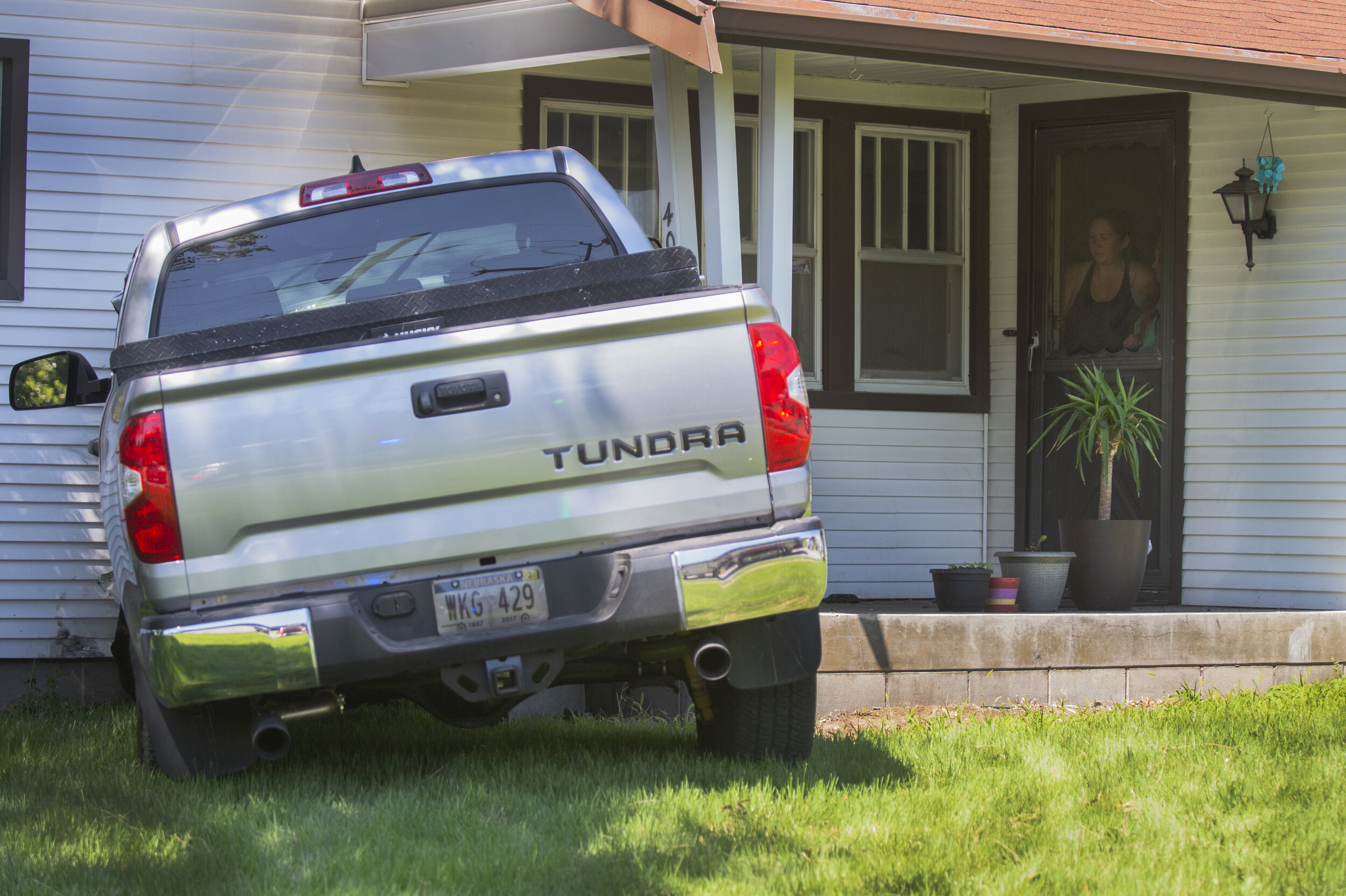  Homeowners peek out from their front door at a Toyota Tundra that careened into the side of their home after a two-vehicle collision at the intersection of 56th and R St. on Friday, July 10, 2020, in Lincoln, Nebraska. One person was taken to the ho