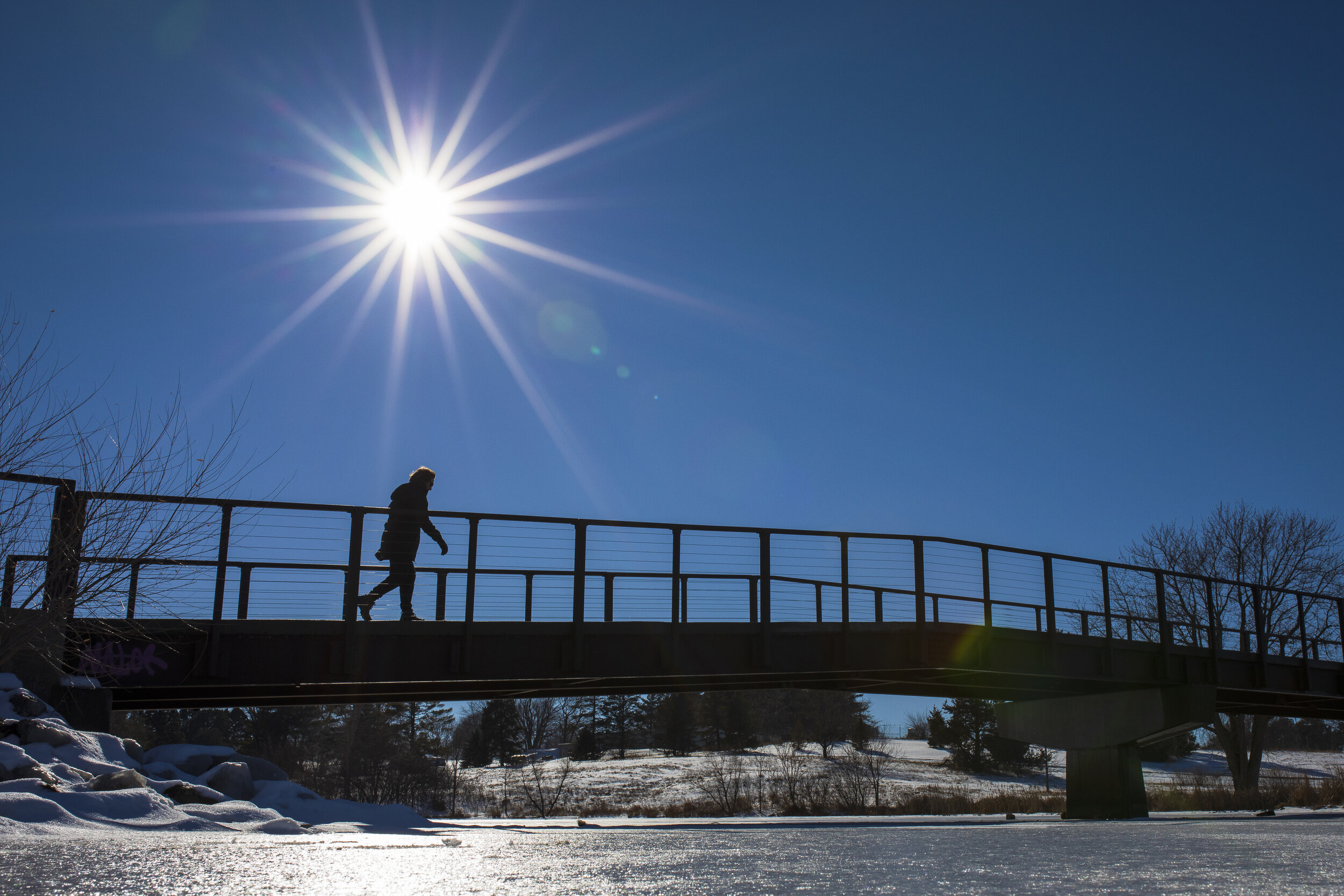  A pedestrian crosses over a footbridge during their walk through Holmes Lake Park on Monday, January 04, 2021. A warm and sunny day brought out all kinds of creatures out of their dens. After last weeks heavy snow, High temperatures in the upper 40s