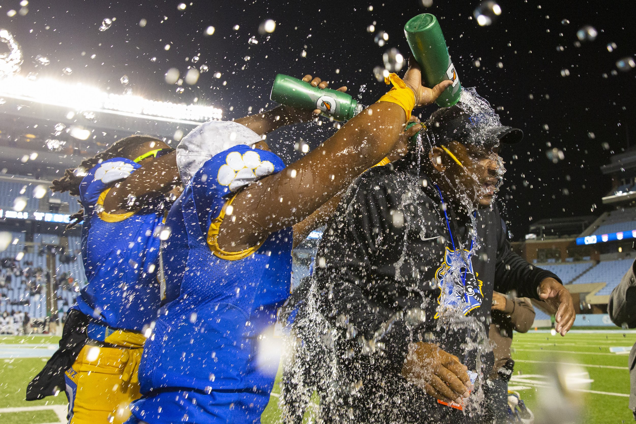  Dudley's Mehki Wall and Jeremiah Barnes dump their water bottles on to head coach Steven Davis after securing their 69-40 win over J.H. Rose during the final seconds of the 3A Football Championship Match at Kenan Memorial Stadium in Chapel Hill, N.C