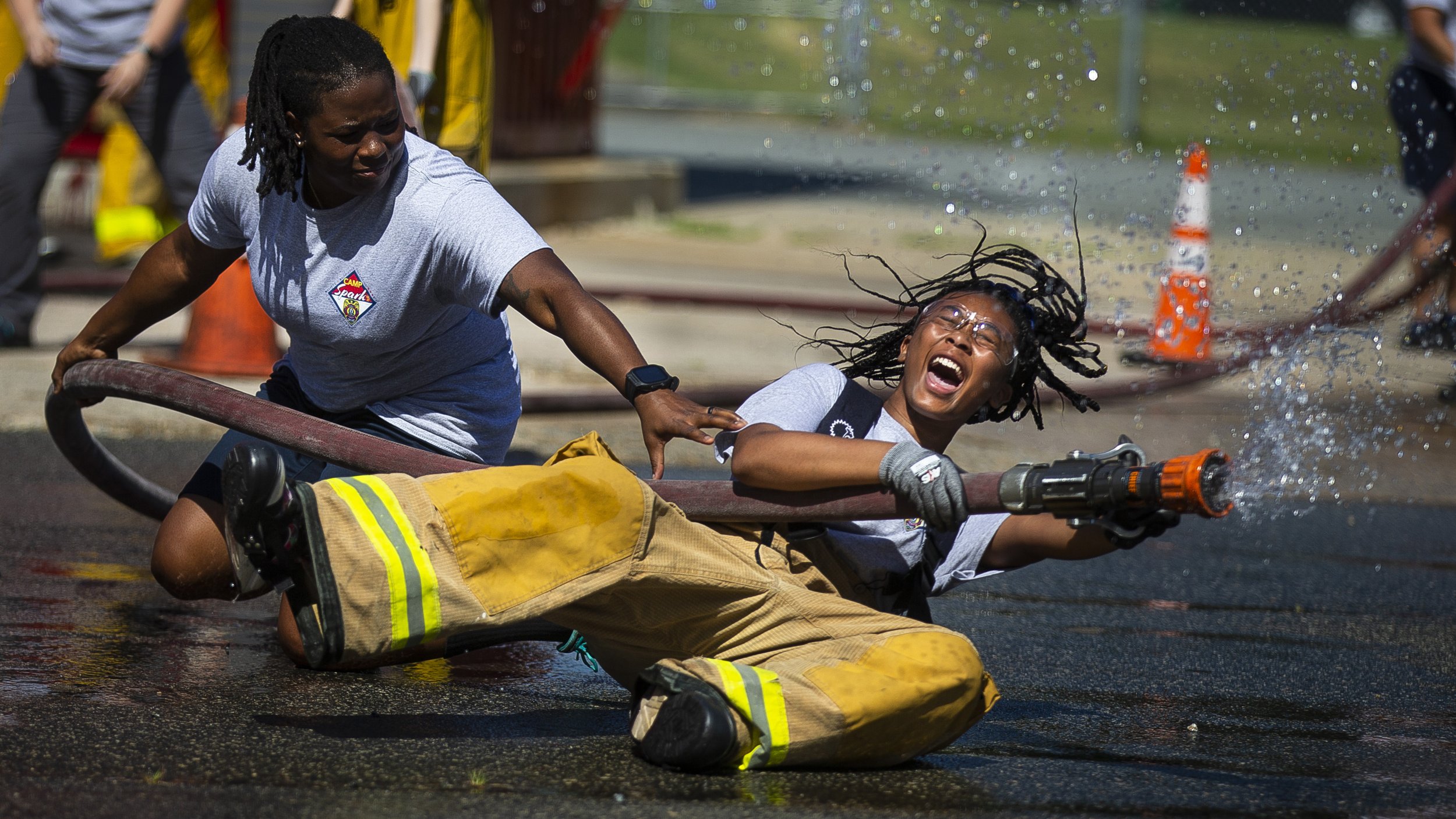 Nebaeh Murphy is knocked back by the force of the hose while training hose deployment during the first day of Camp Spark at the Greensboro Fire Department's training grounds in Greensboro, N.C., on Monday, July 12, 2021.   Camp Spark, a free four da