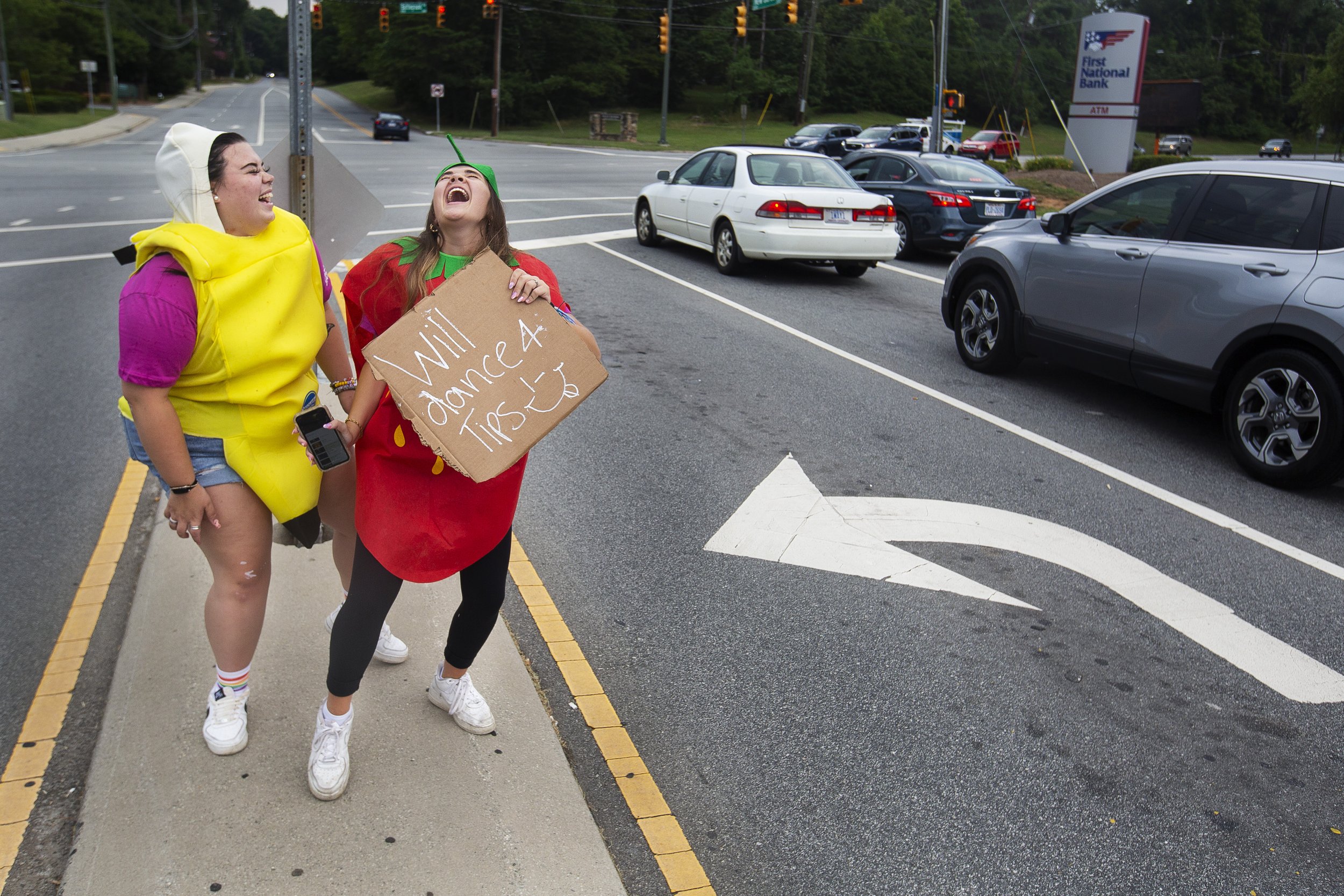 Dressed as a banana and strawberry, Grayson Kanoy (left) and Anna Conahan dance for tips while on break from Tropical Cafe at the intersection of New Garden Road and Battleground in Greensboro, N.C., on Friday, July 16, 2021. The pair said they were