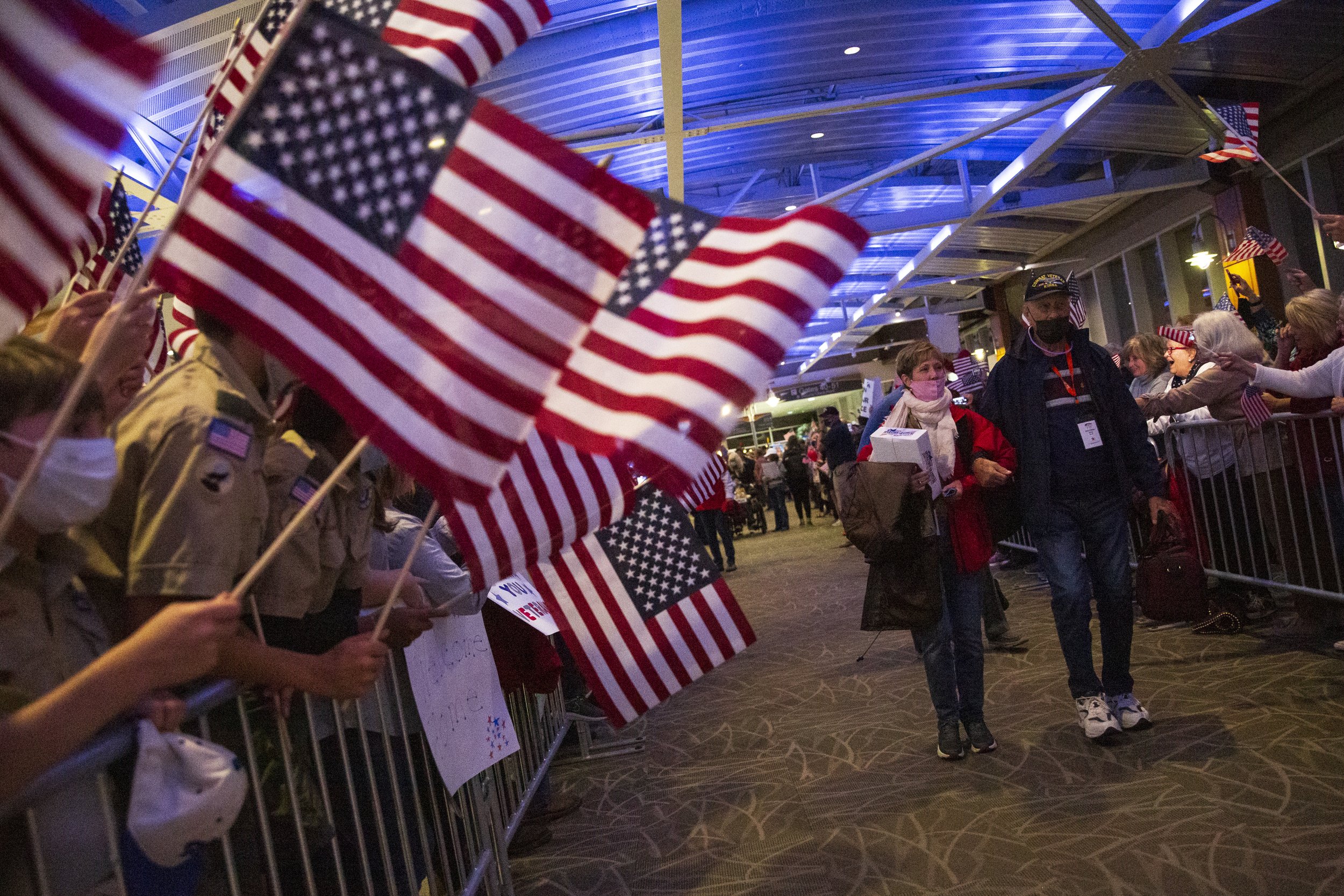  Veterans walk down a path of friends and family members welcoming them home during the return of the Triad Honor Flight at the Piedmont Triad International Airport in Greensboro, N.C., on Thursday, November 11, 2021.     