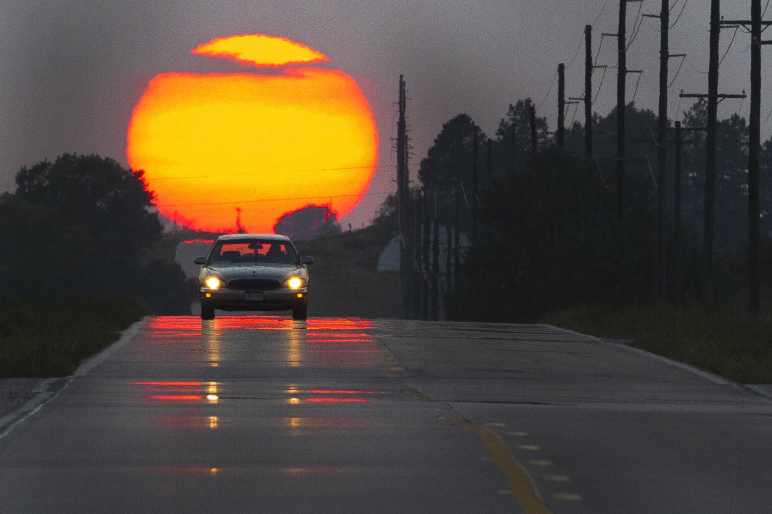  A driver makes their way east as the sun, obscured by smoke from wildfires burning in western Nebraska, sets behind them Monday, September 21, 2020, in Denton, Nebraska.  